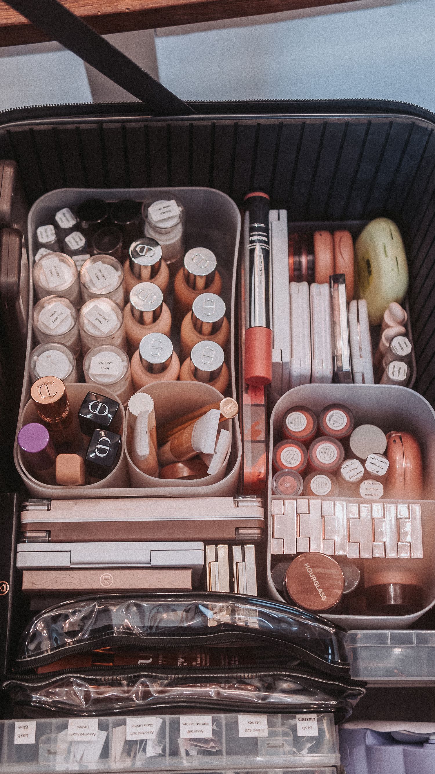 Organized makeup collection in a travel case with foundations, lipsticks, and beauty products neatly arranged in compartments.