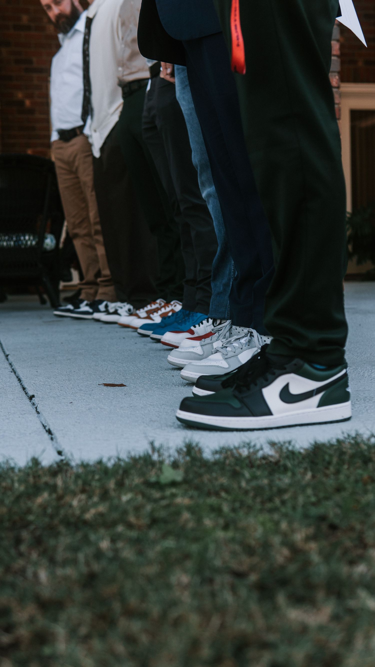 Group of people standing in a line showing off their Nike Air Jordan sneakers on a concrete surface.