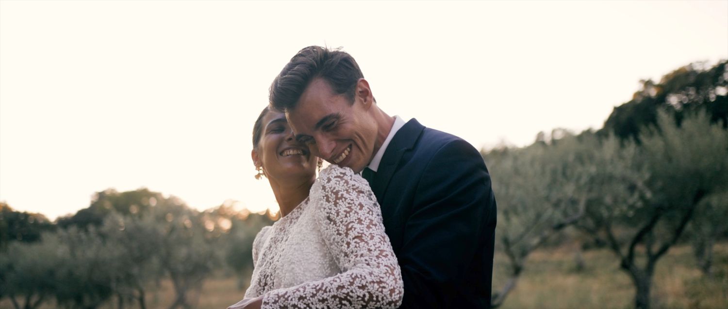 A couple sharing a joyful moment against a sunset backdrop.
