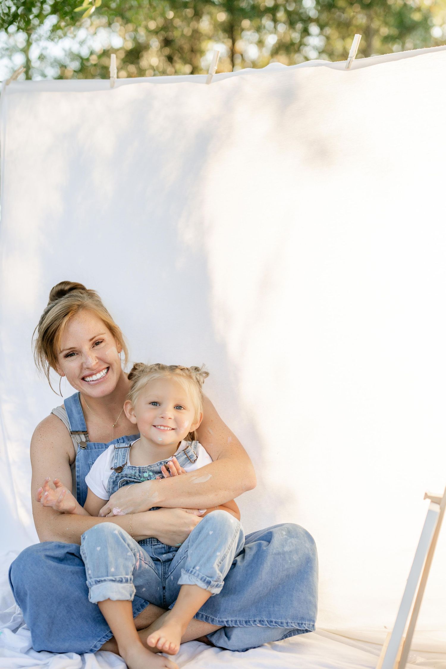 A tender moment captured against a white wall as parent and child in matching denim share loving embraces.