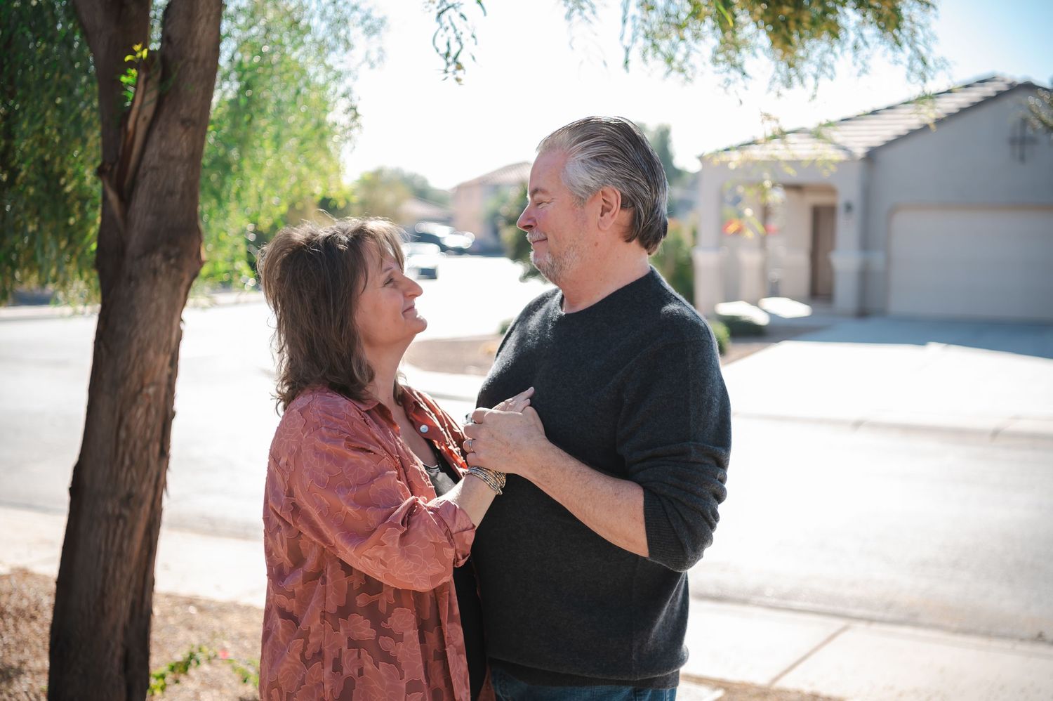 Couple interacting outdoors on a sunny day near residential buildings.