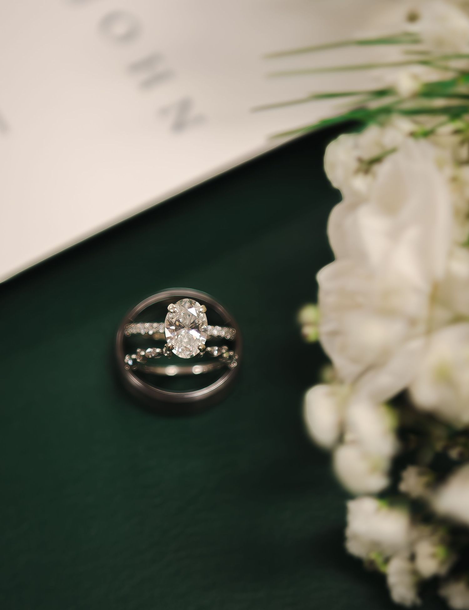Diamond engagement ring with white flowers against a dark background.