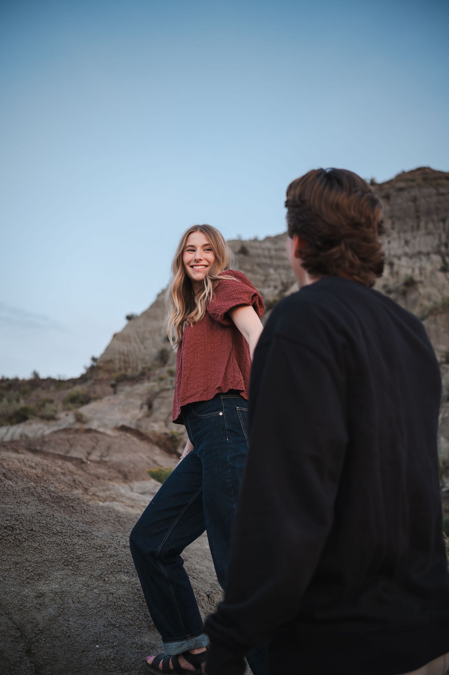 Couple sharing playful moments on rocky terrain at dusk.