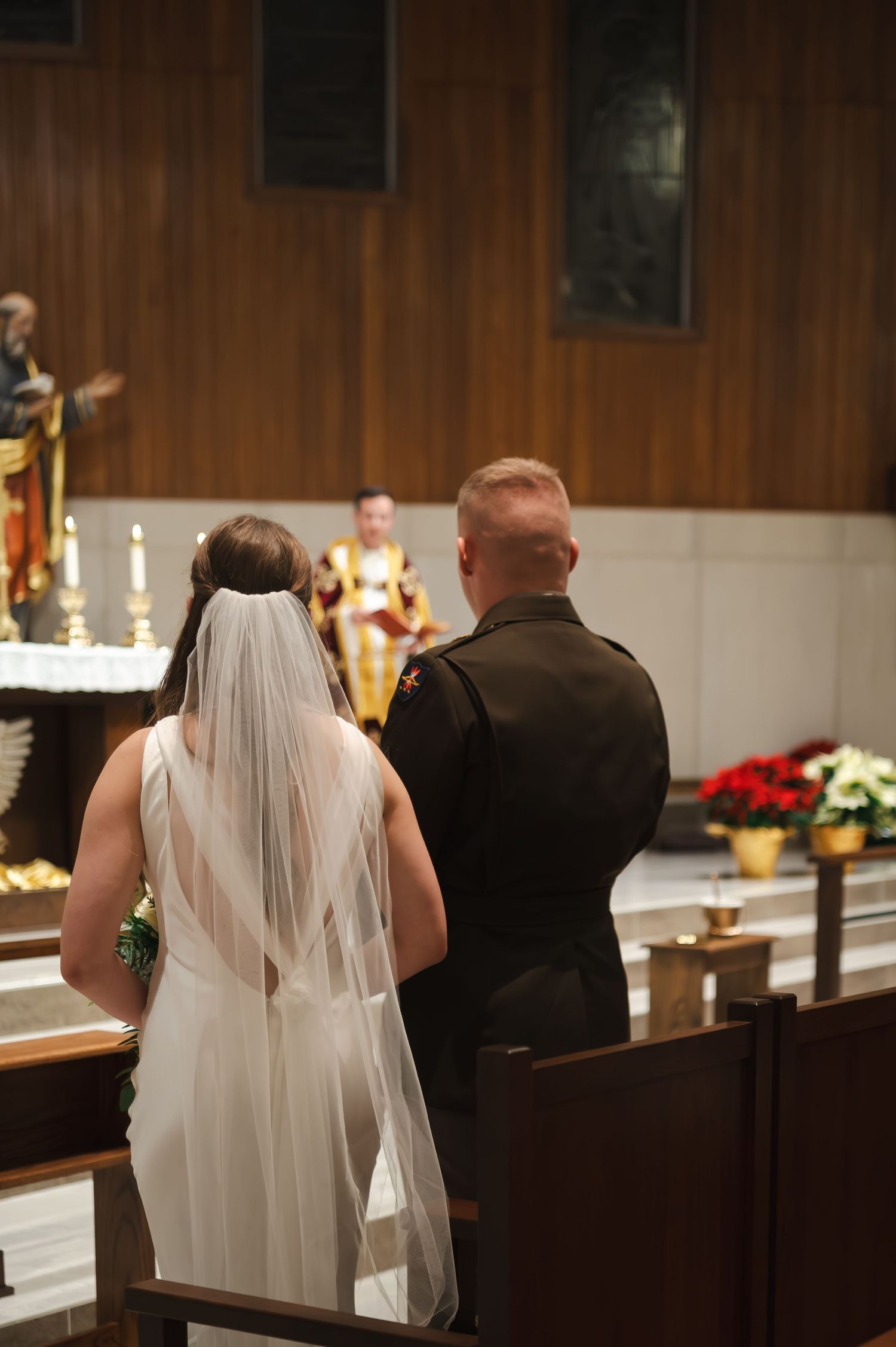 Wedding ceremony attendees seated in wooden pews inside a church with warm lighting.