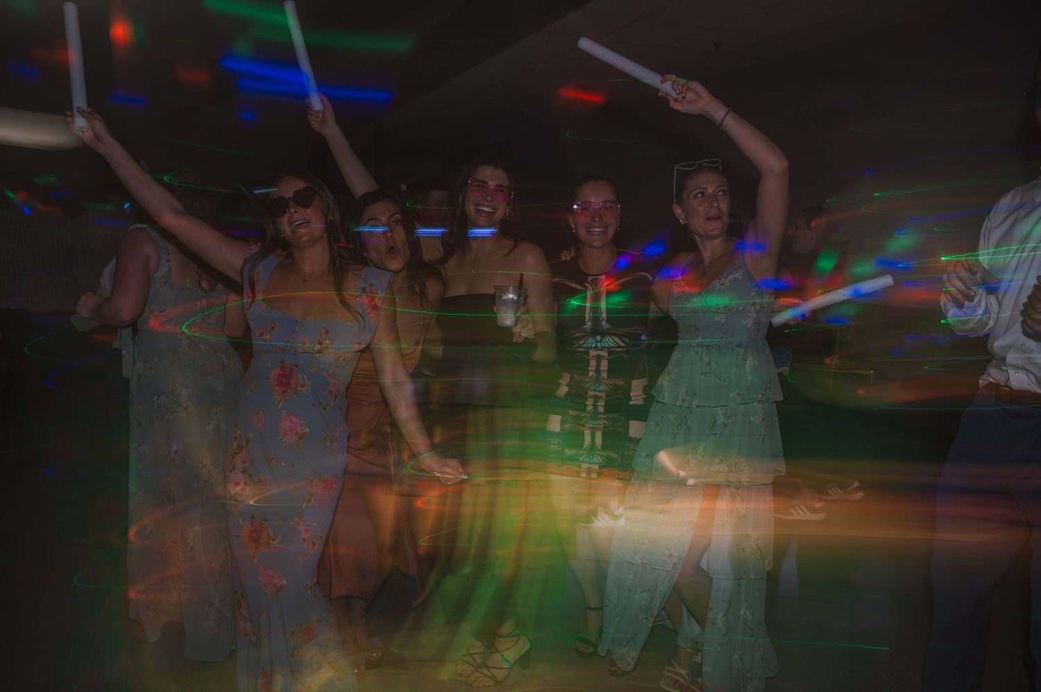 Blurred party scene with colorful disco lights and dancing silhouettes.