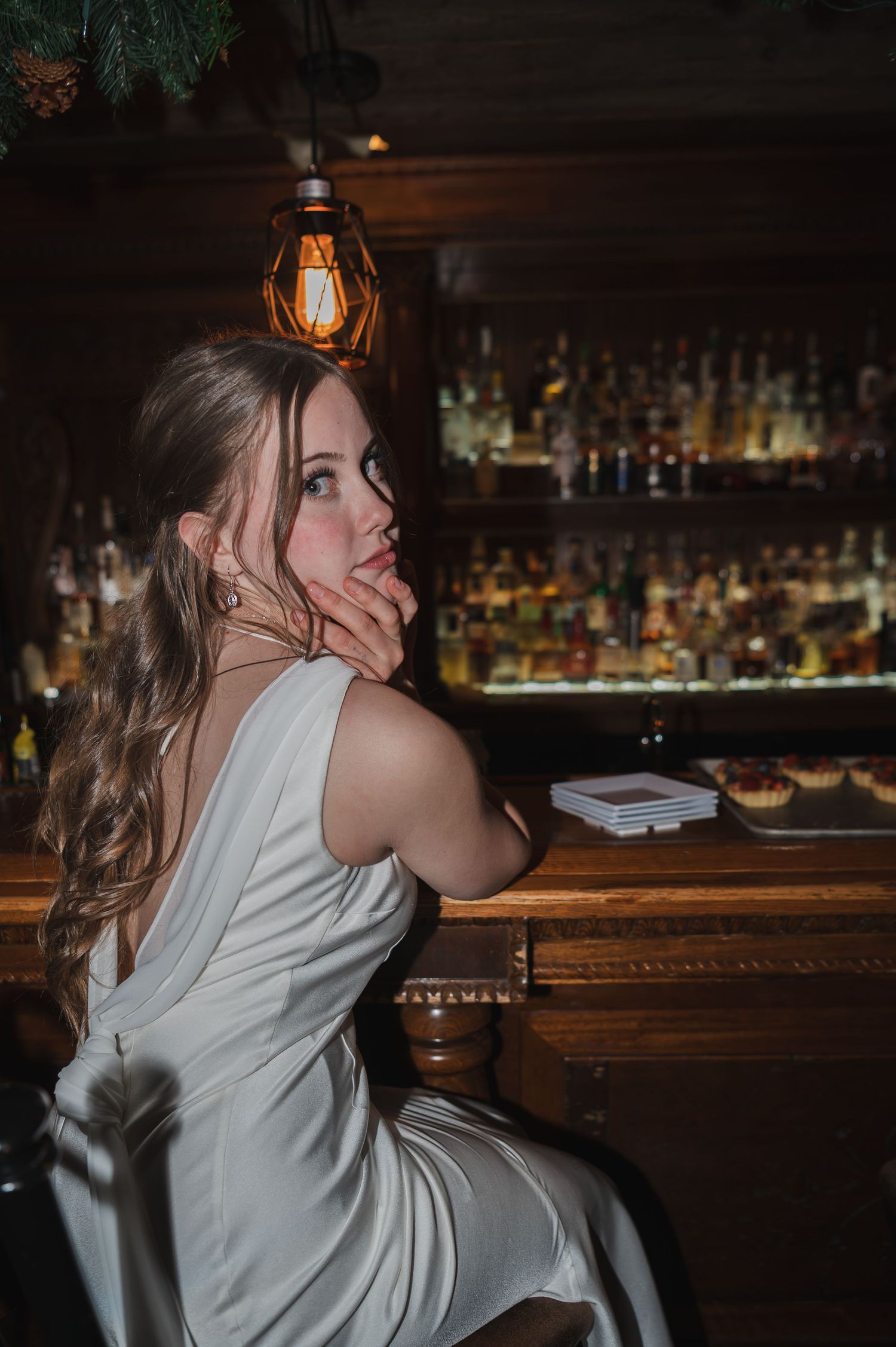 Woman in white shirt dancing and moving in a rustic bar setting with warm lighting.