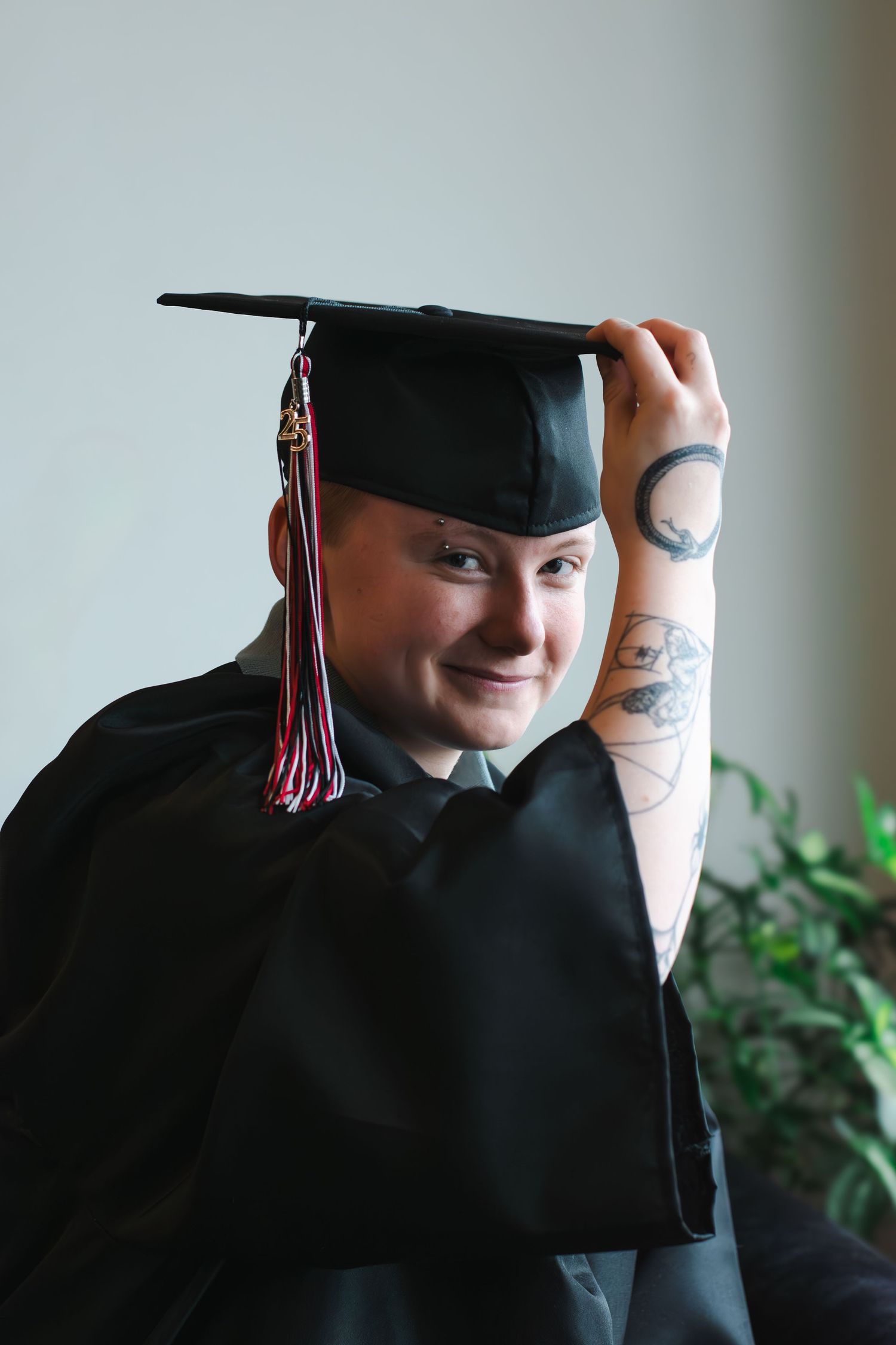 Graduation photoshoot showing a person in black cap and gown with decorative tassel.