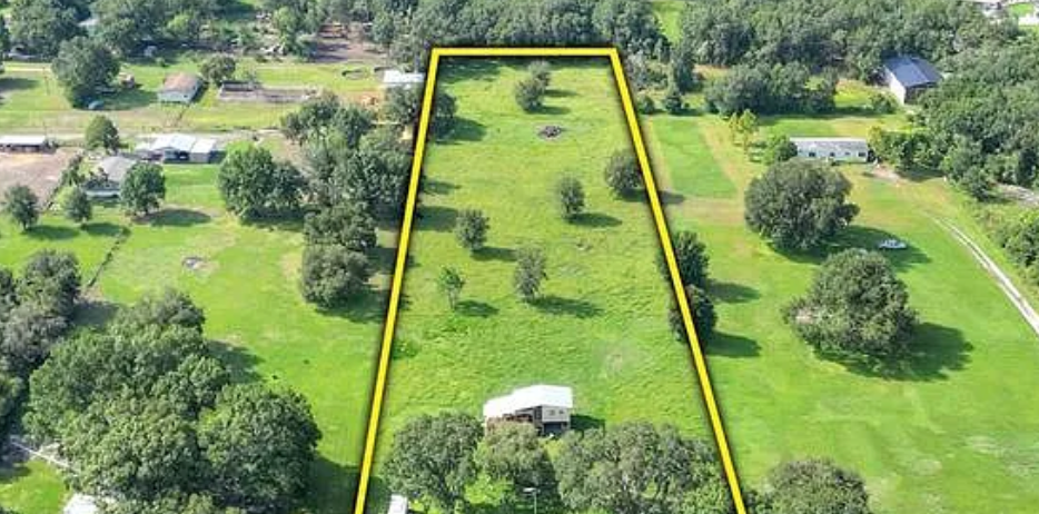 Aerial view of a lush golf course with winding paths, green fairways and scattered trees in a scenic landscape.