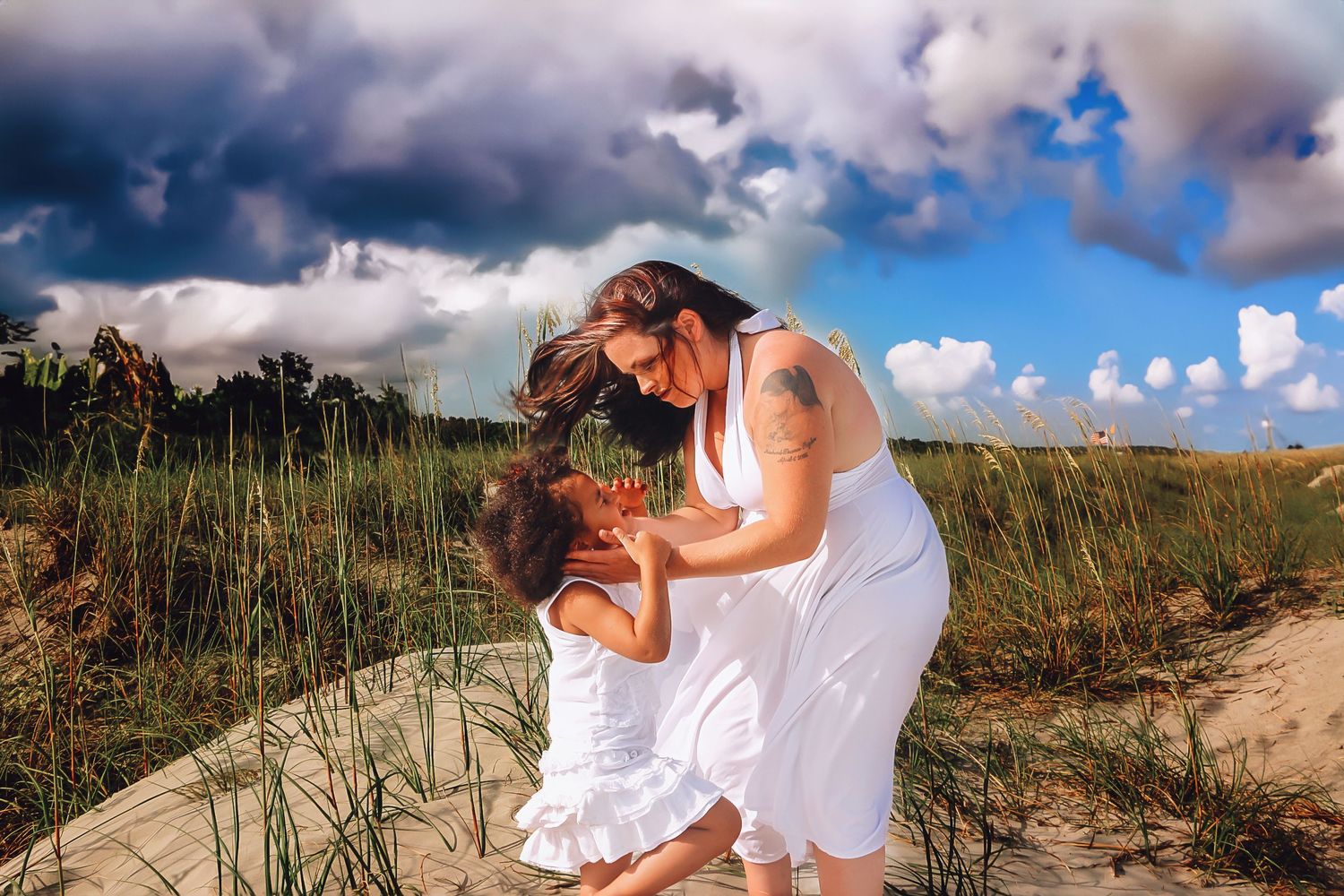 Mother wipes sand from her daughter's eyes.