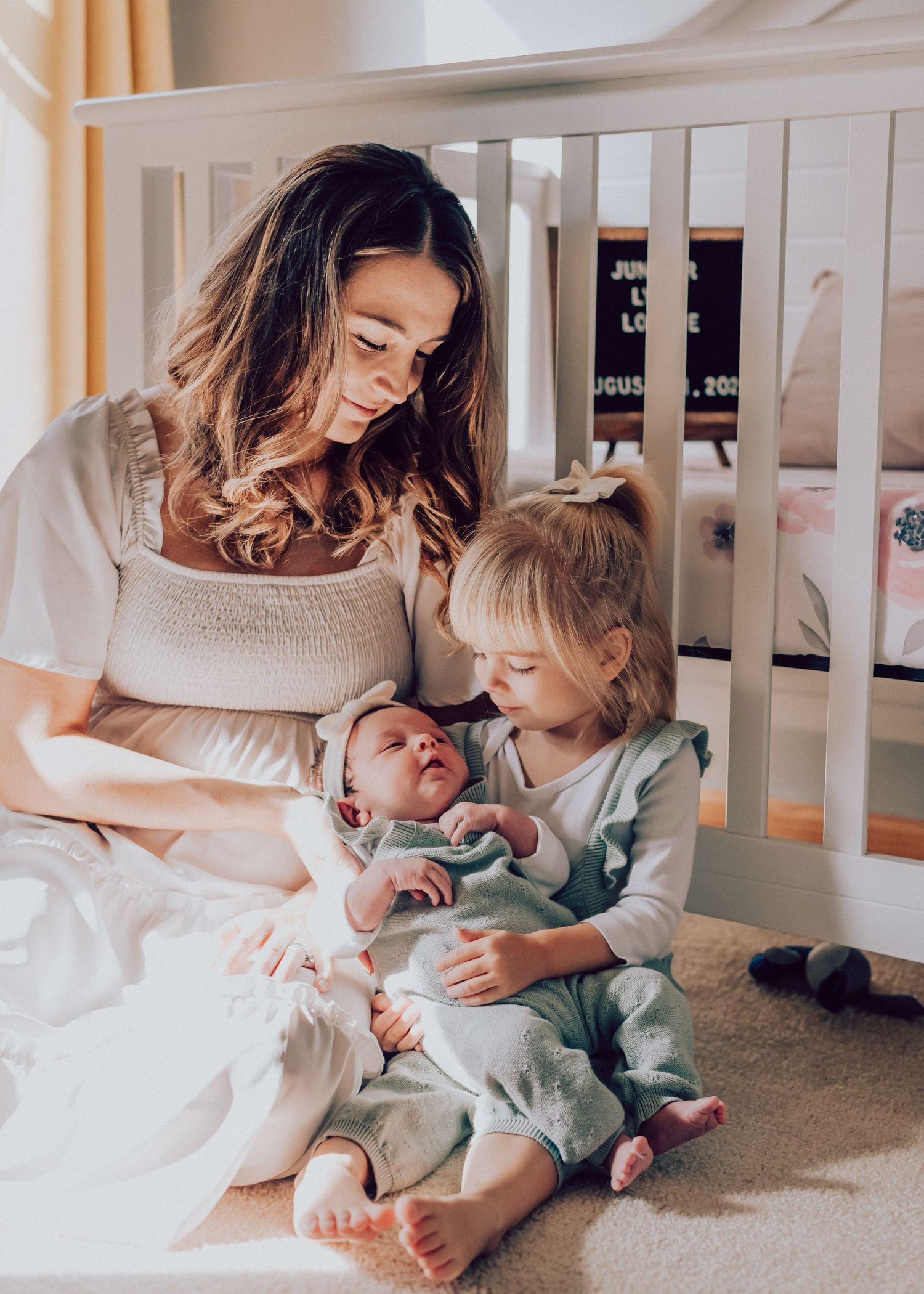 An image of mom and daughter and baby sitting in the nursery, taken by Life Well Spent Photography