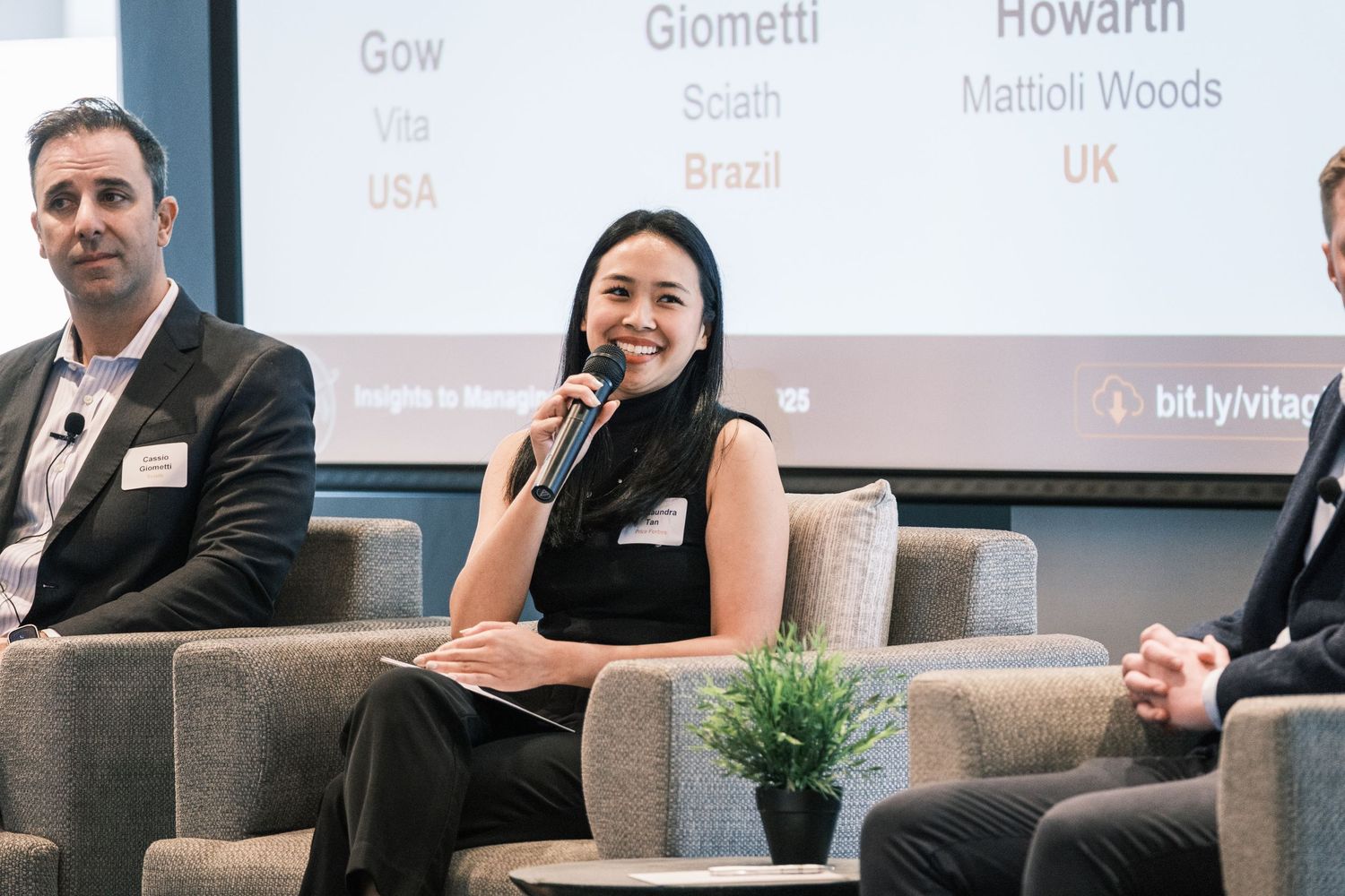Professional panel discussion taking place on stage with speakers seated in comfortable chairs.