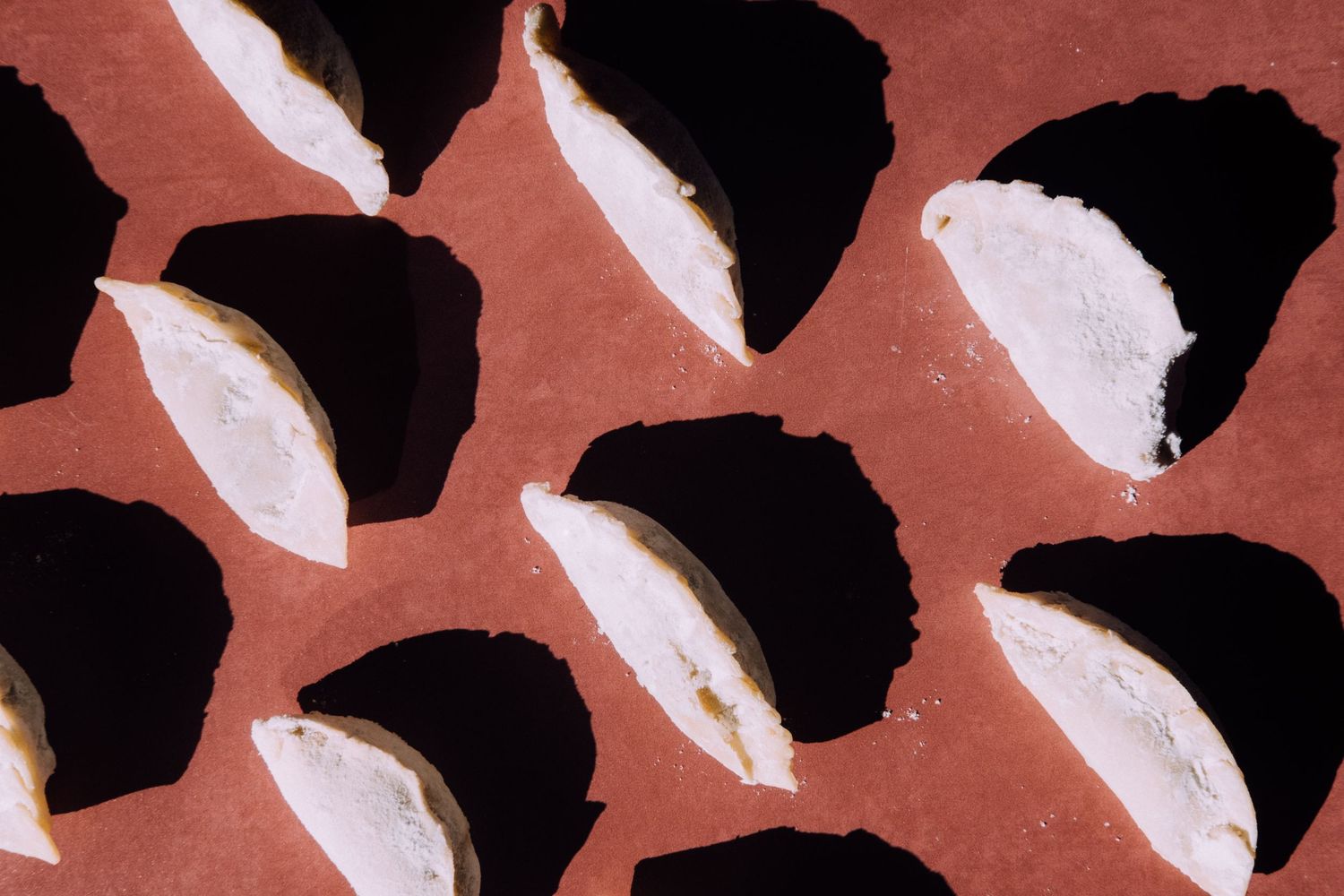 Abstract pattern of black and white semi-circular shapes arranged on a coral colored background.