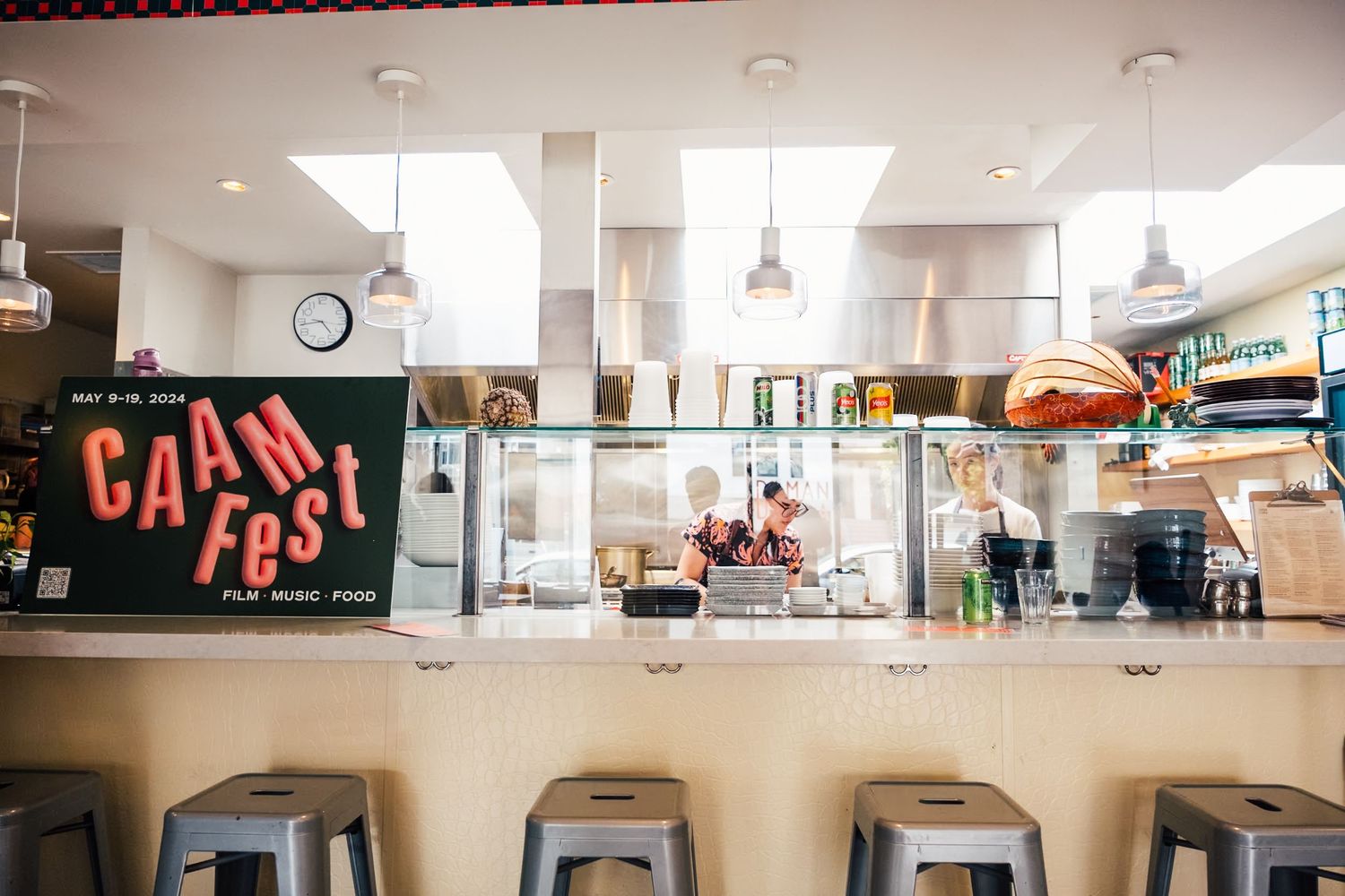 Bright interior of a modern cafeteria space with hanging pendant lights and white walls.
