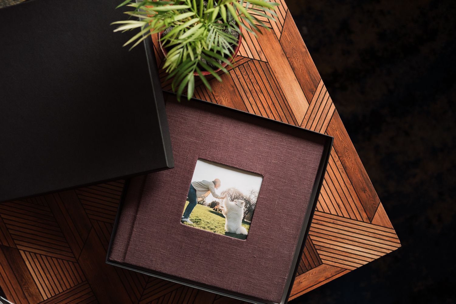 Elegant burgundy photo album with printed cover image displayed in black gift box on wooden surface.