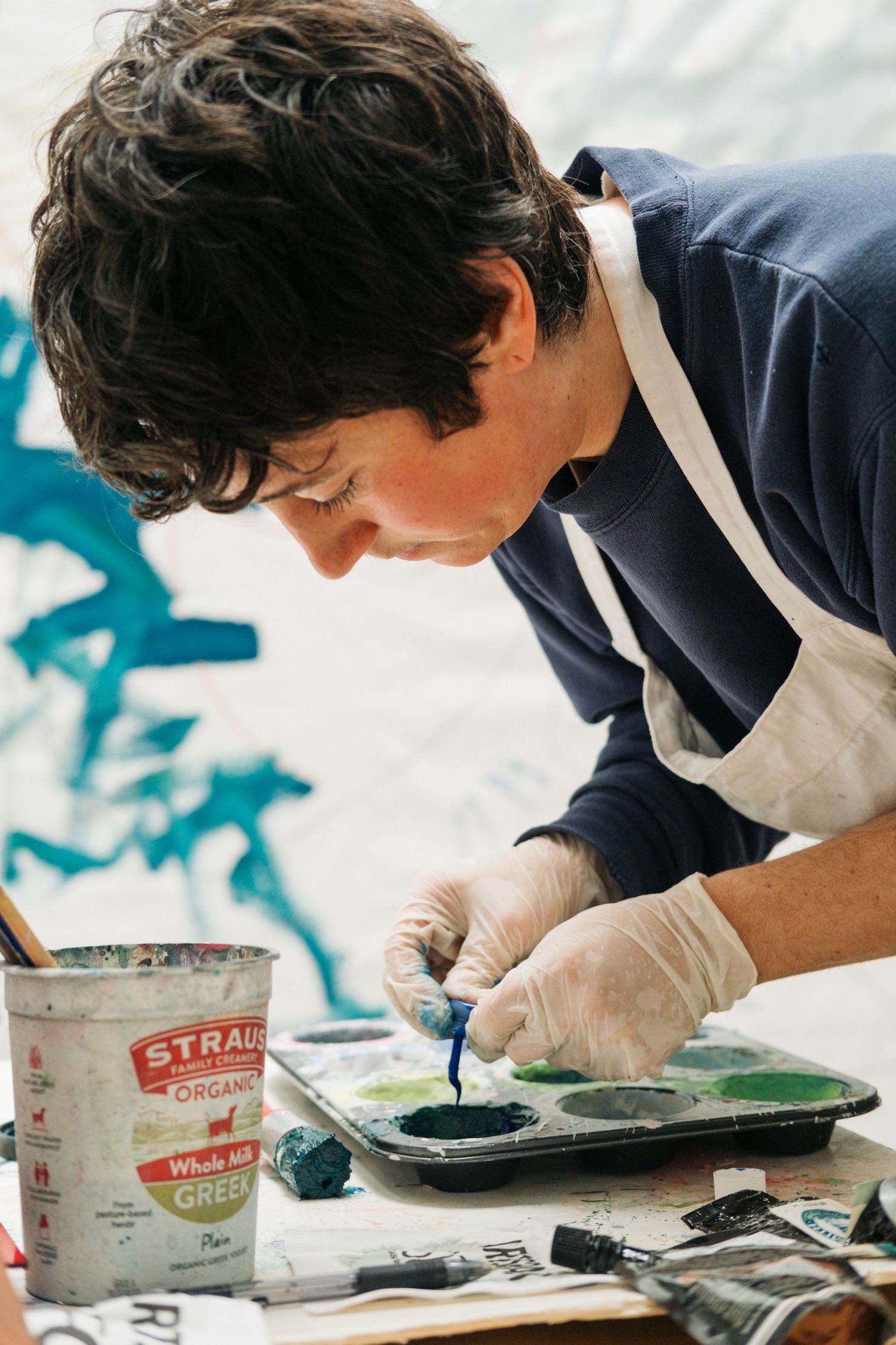 Person in navy shirt and white gloves works carefully with materials on a flat surface during a craft project.