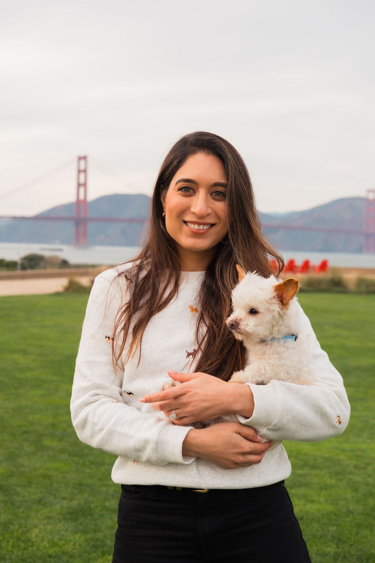Dog company owner and entrepreneur holding a small white dog. Lifestyle headshot/portrait photo taken outside in San Francisco Presidio.