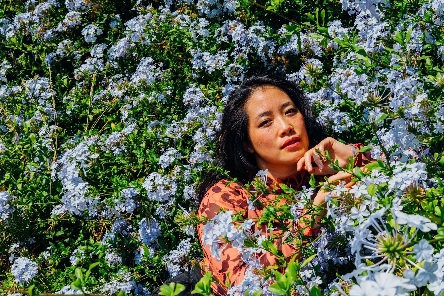 Colorful, outdoor, creative portrait of an Asian-American woman with flowers taken by professional photographer Jenn Chen in San Francisco