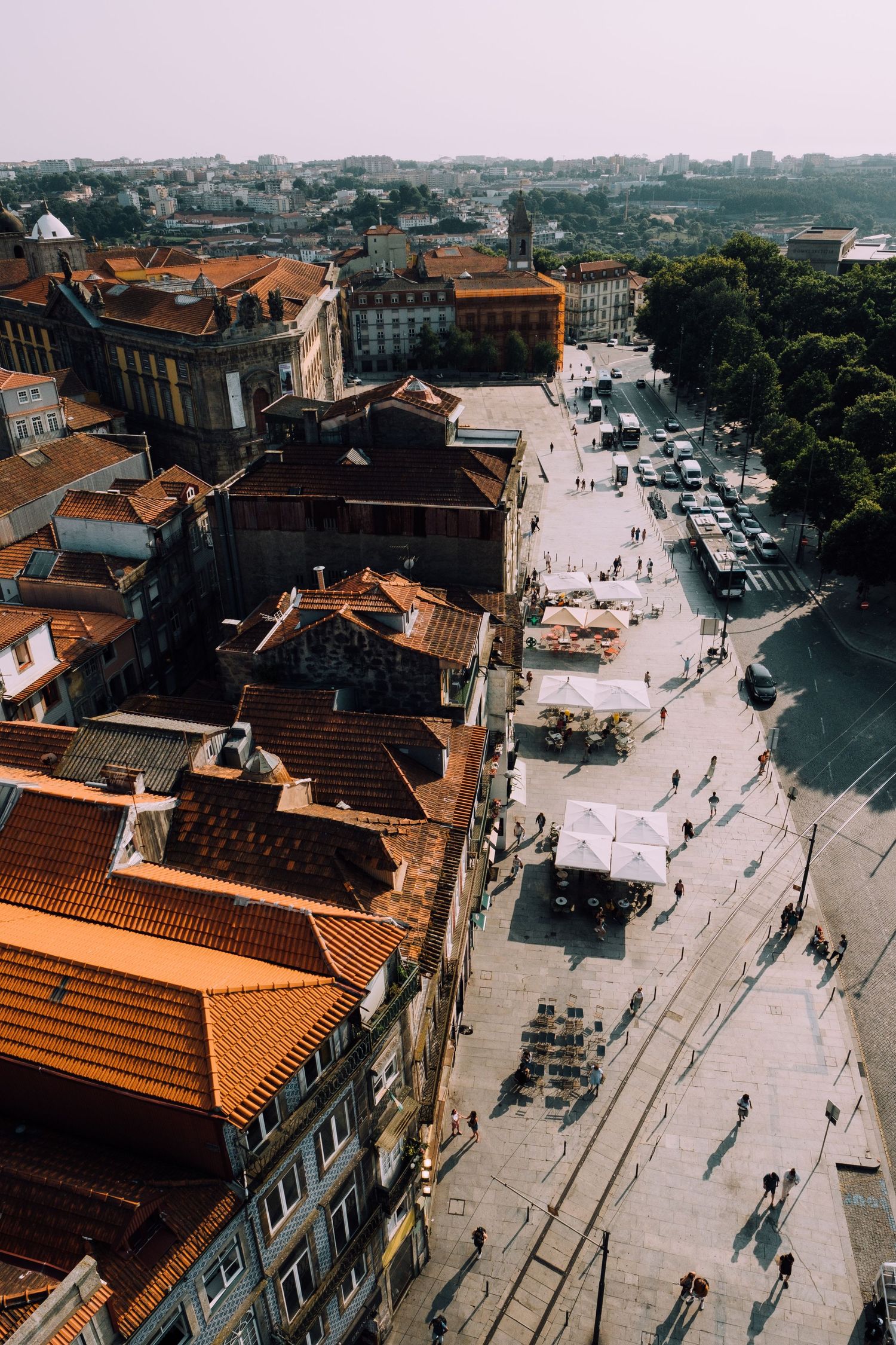 Aerial view of historic Porto streets with traditional orange-tiled roofs and pedestrians below.