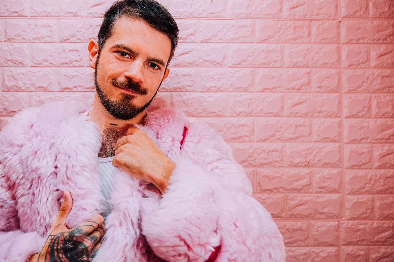 Hero shot of fun, creative consultant. Person wearing a pink fur jacket against pink brick wall. Personal branding photographer in SF.