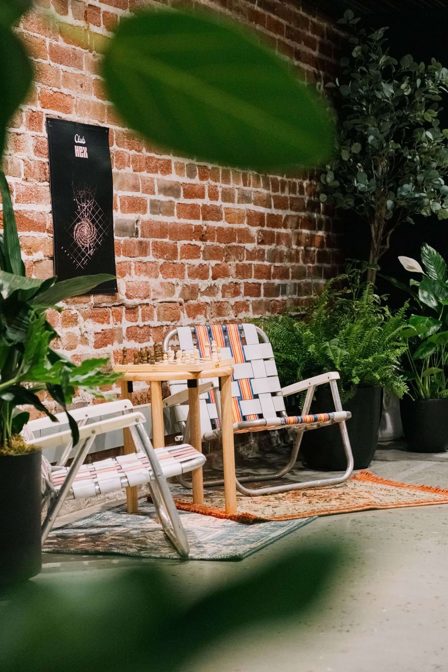Wooden benches arranged against a brick wall with potted plants creating an outdoor seating area.