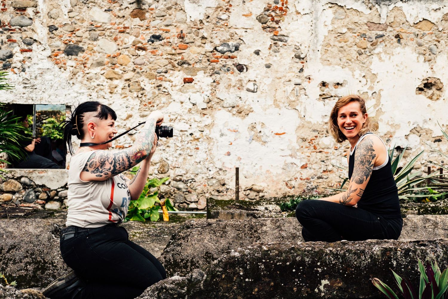 Two people taking photos on old stone wall ruins.