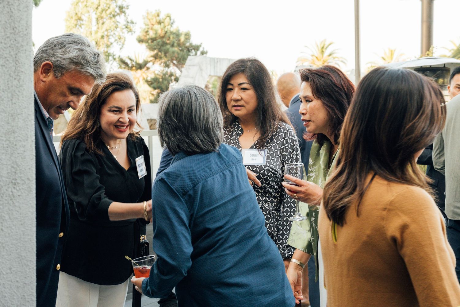 Diverse group of professionals mingling and networking at a business event with cocktails and drinks.