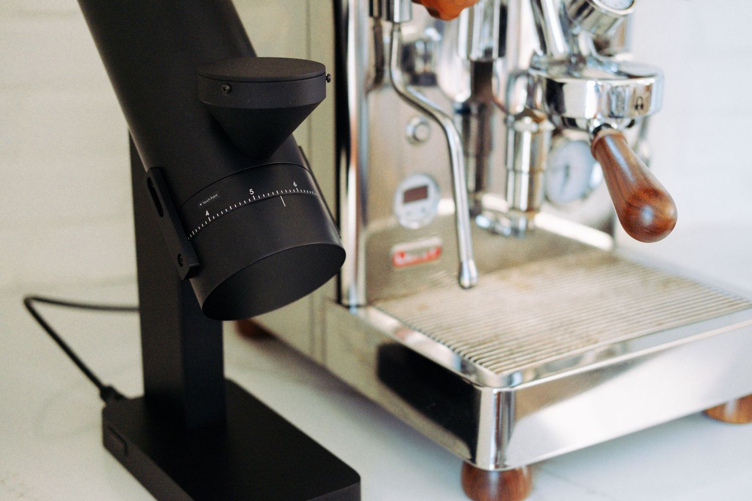 Modern black coffee grinder next to espresso machine on counter.