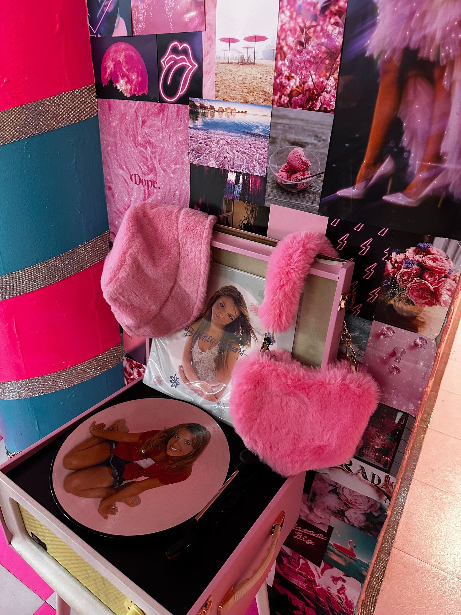 A pink-themed collage wall with photos, a pink heart pillow, and decorative accents in bright magenta and blue tones.