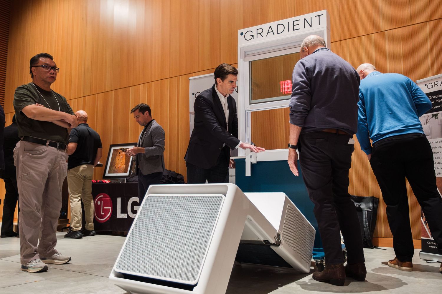 People examine LG and Gradient HVAC products at an indoor trade show exhibition event.
