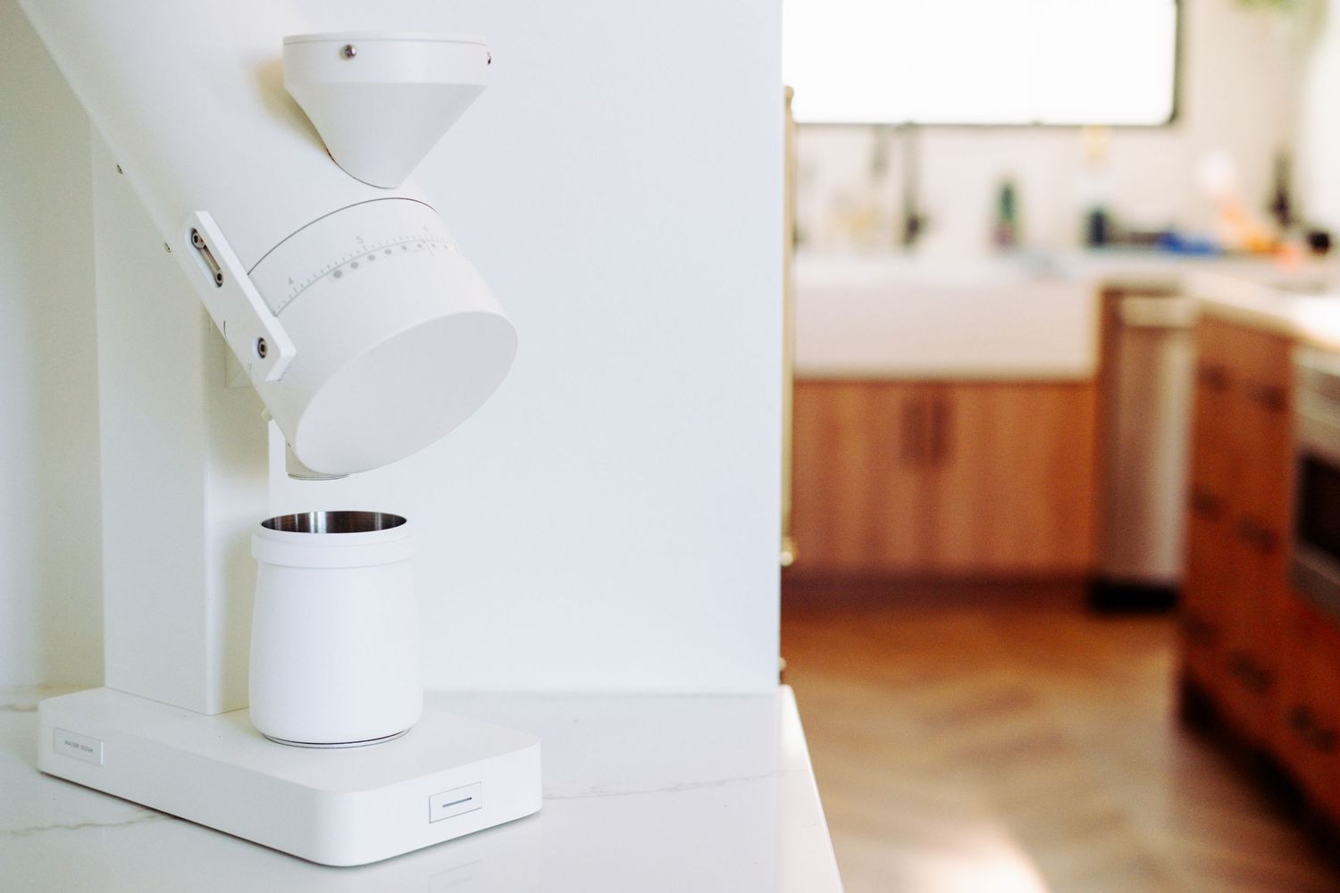 White coffee brewing equipment components arranged against white wall in kitchen setting.