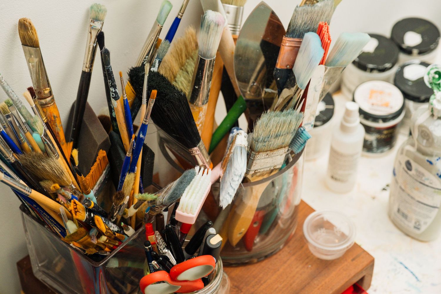 Art supplies and paintbrushes arranged on a white surface with natural lighting.