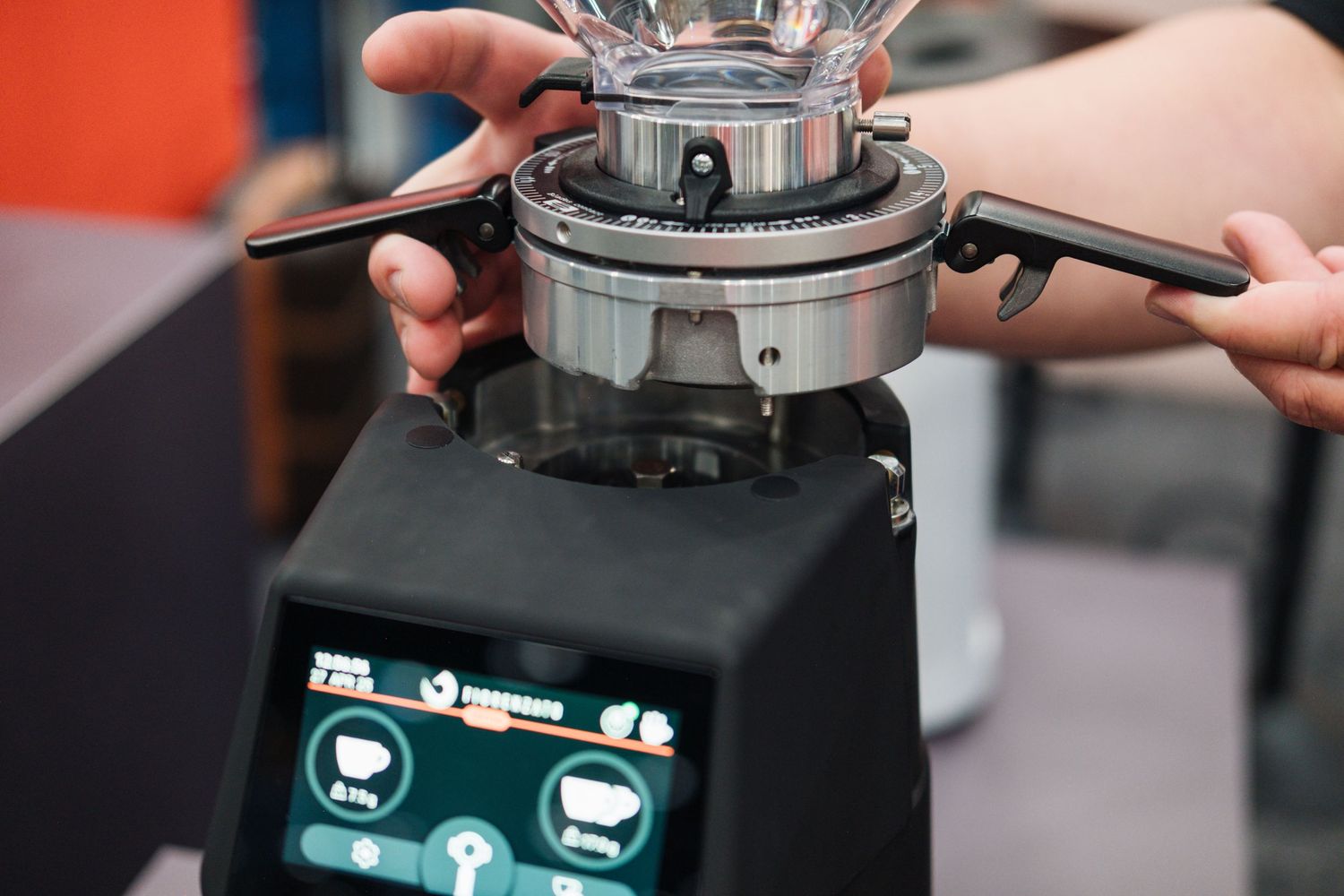 Close-up shot of hands adjusting settings on a professional coffee grinder with digital display.
