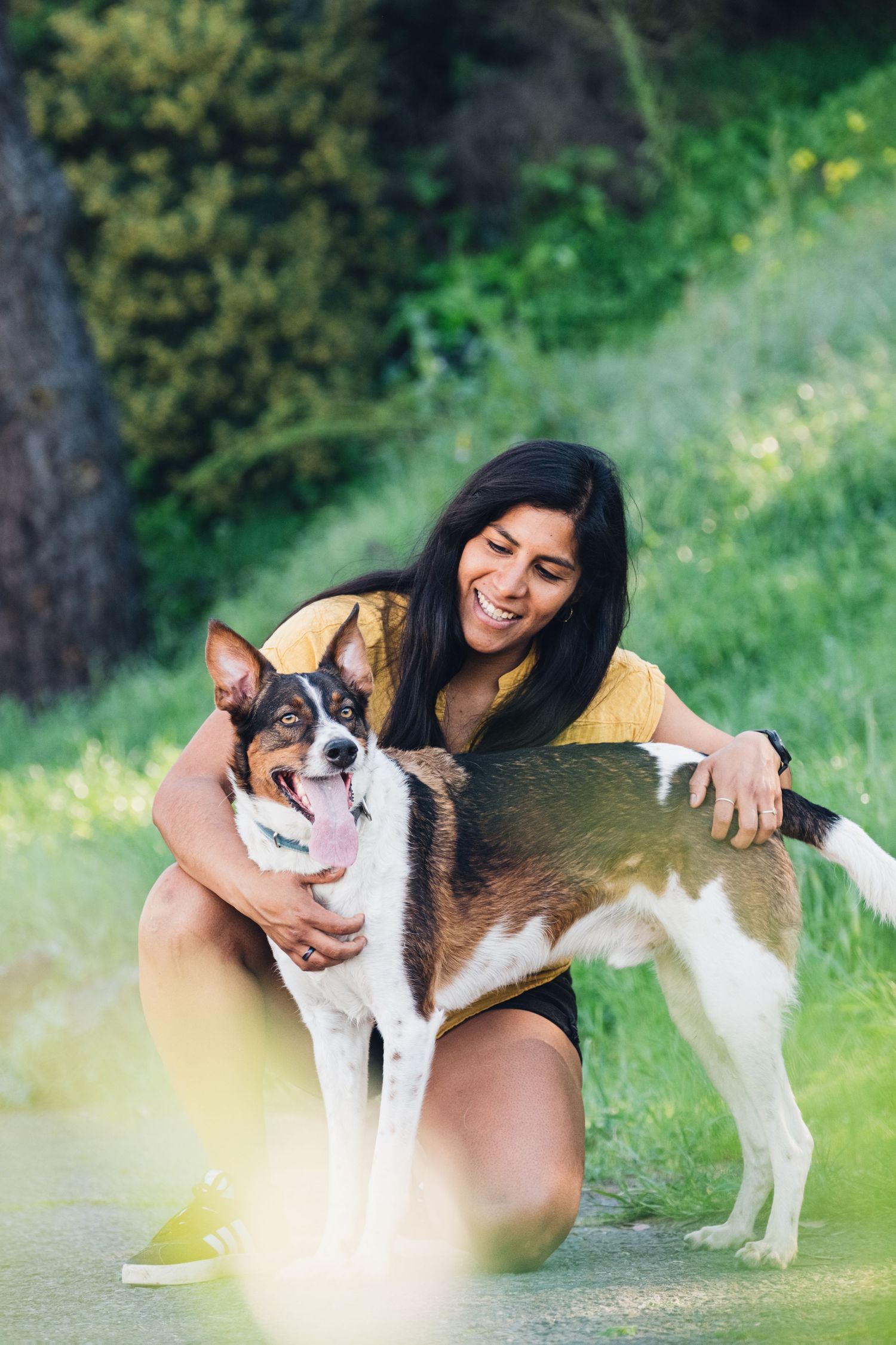 Authentic captured moment of a woman hugging her dog in a peaceful park setting, showing connection and warmth.