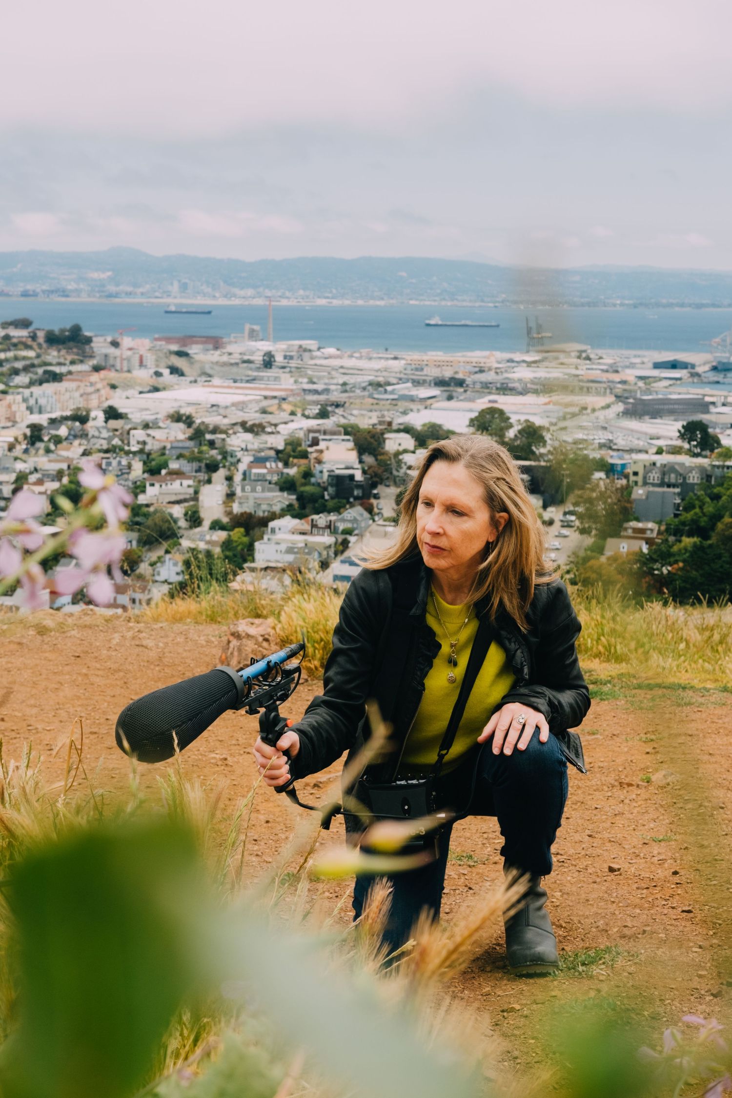 Outdoor personal branding shoot of audio producer in Bernal Heights. Using a mic with San Francisco backdrop, taken by a brand photographer.