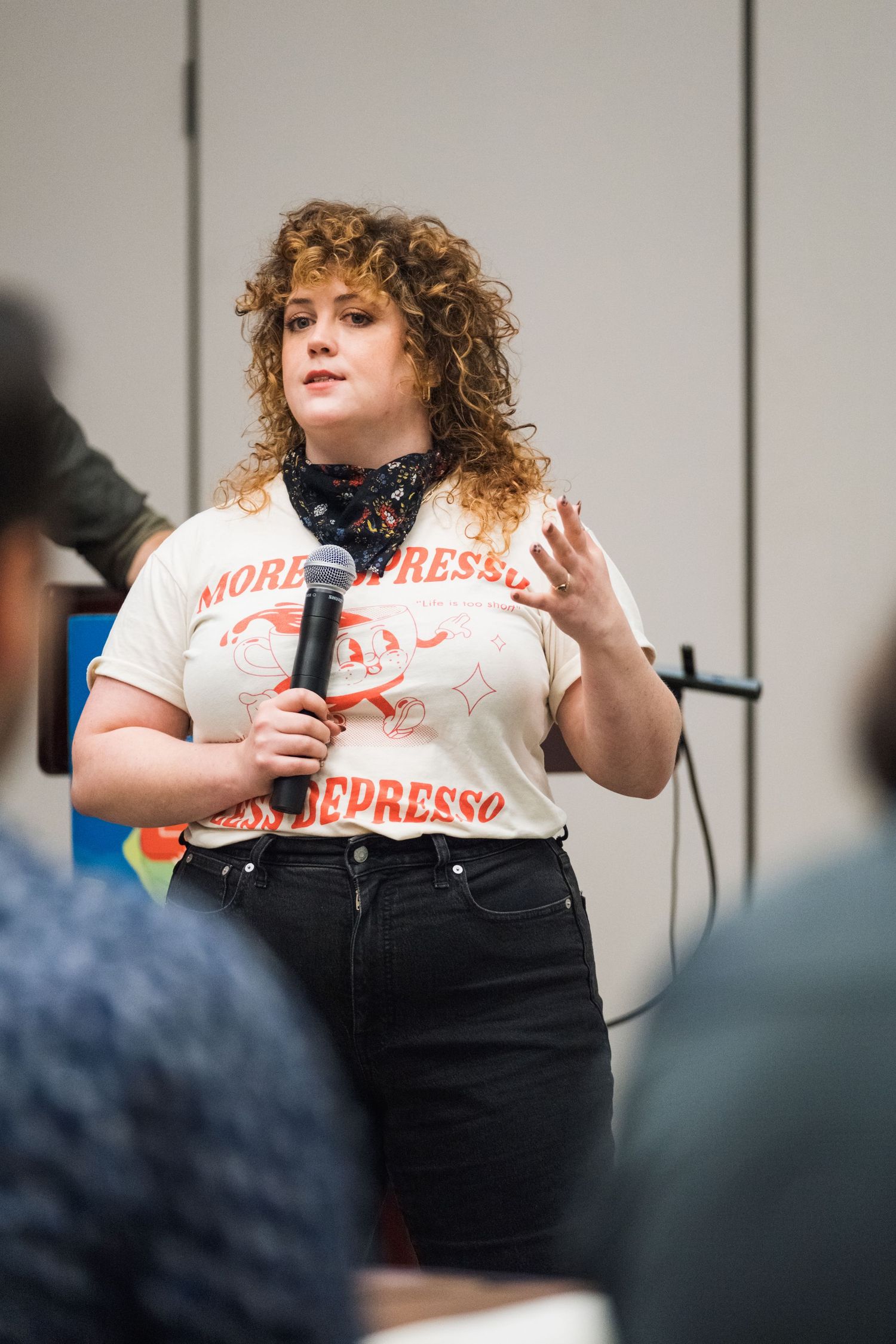 Speaker presenting with microphone wearing casual t-shirt and jeans.