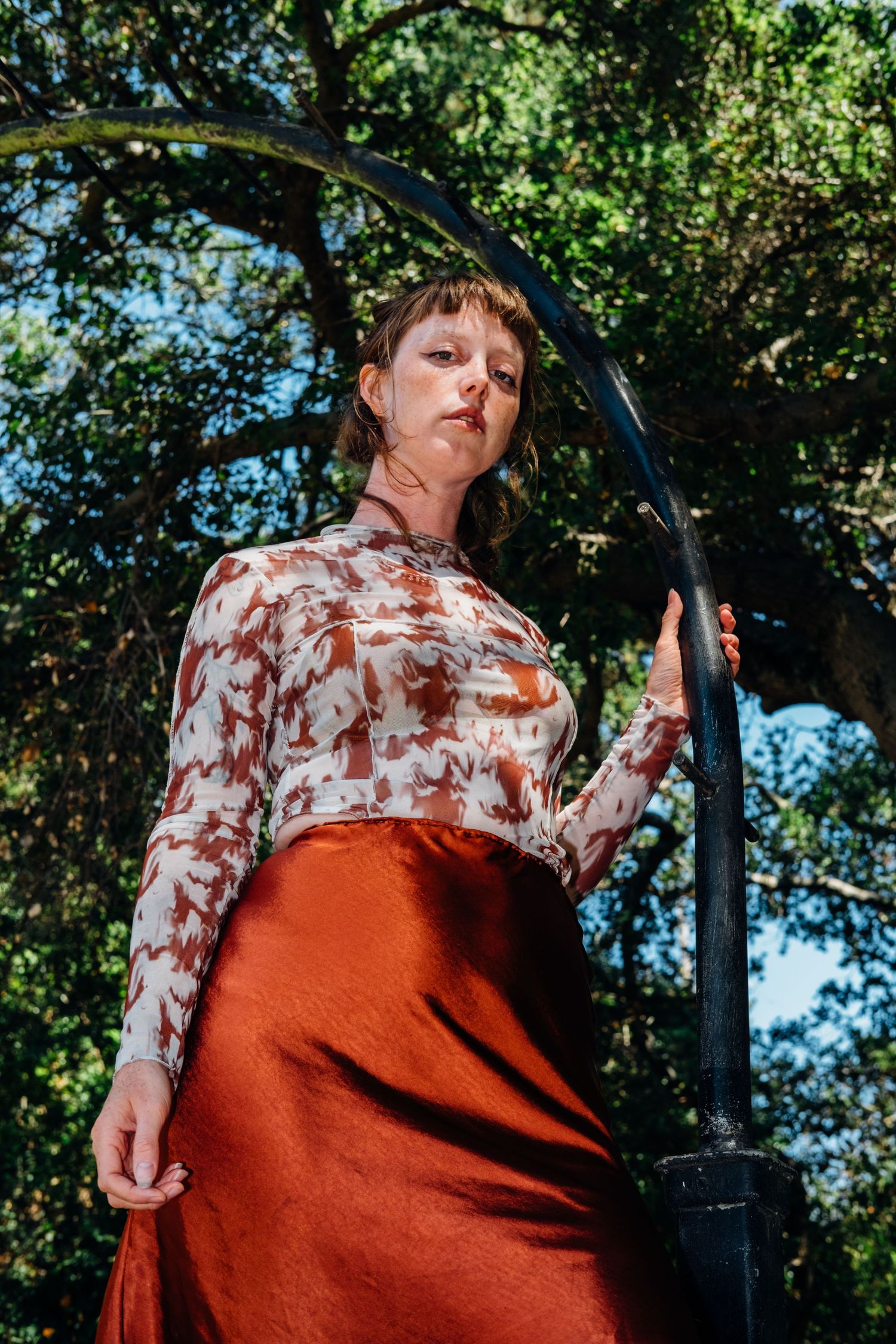 Outdoor fashion portrait against lush greenery and decorative metal arch.