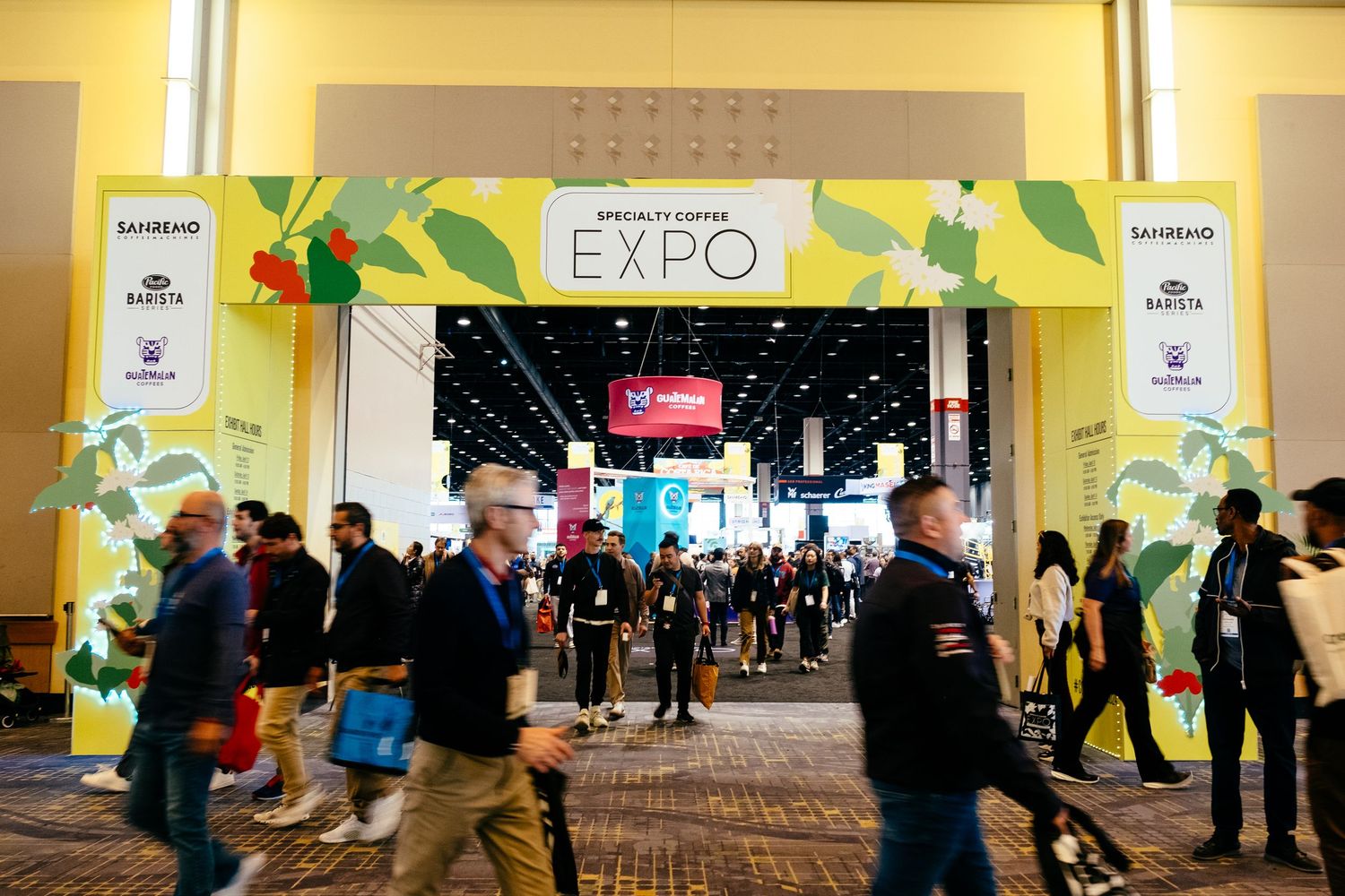 Wide view of a convention hall with yellow banners and expo signage.