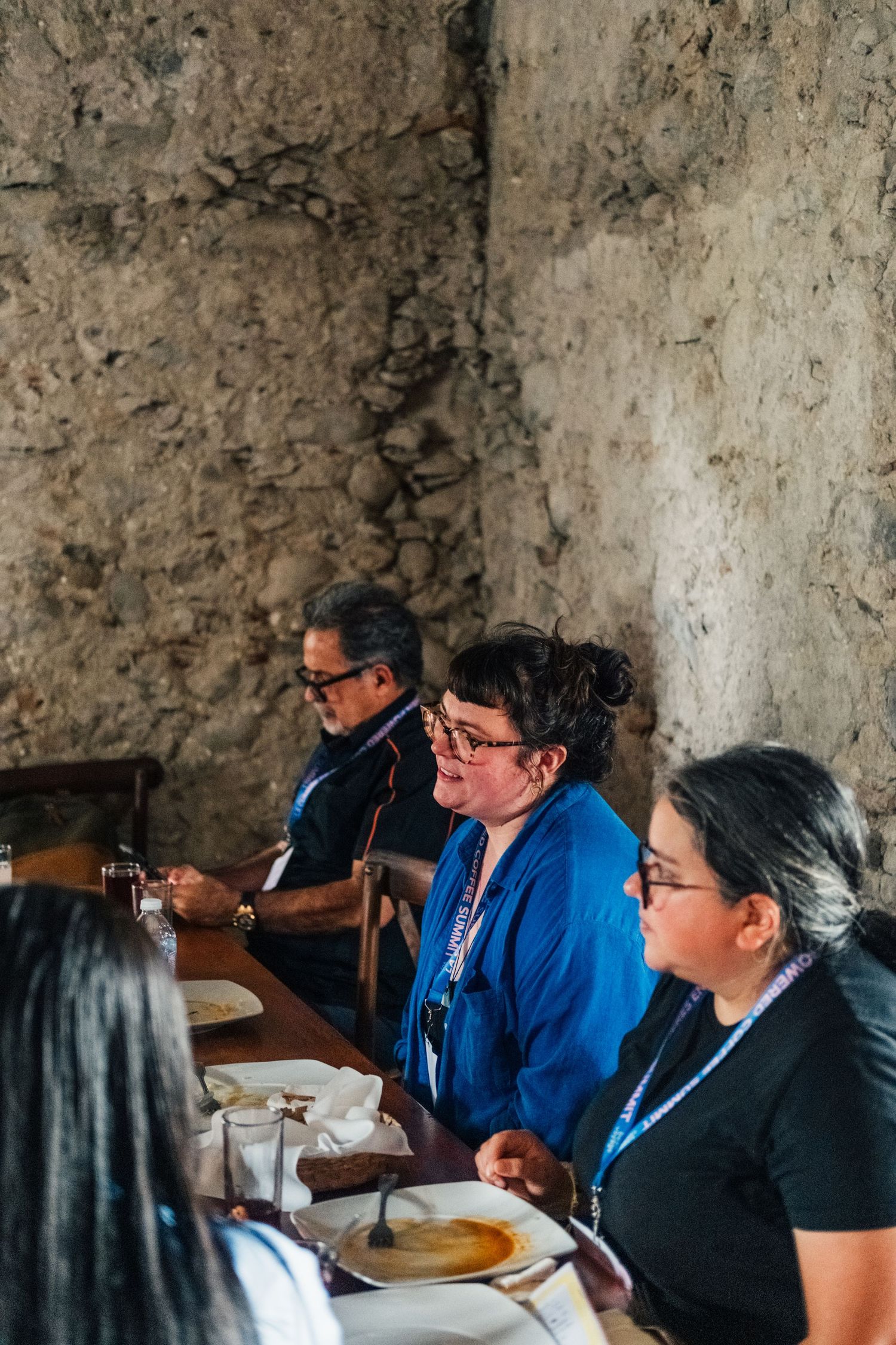 A group of people dining together at a rustic table during an indoor gathering.