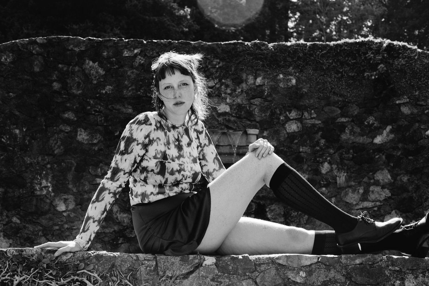 Vintage black and white portrait against textured stone wall outdoors.