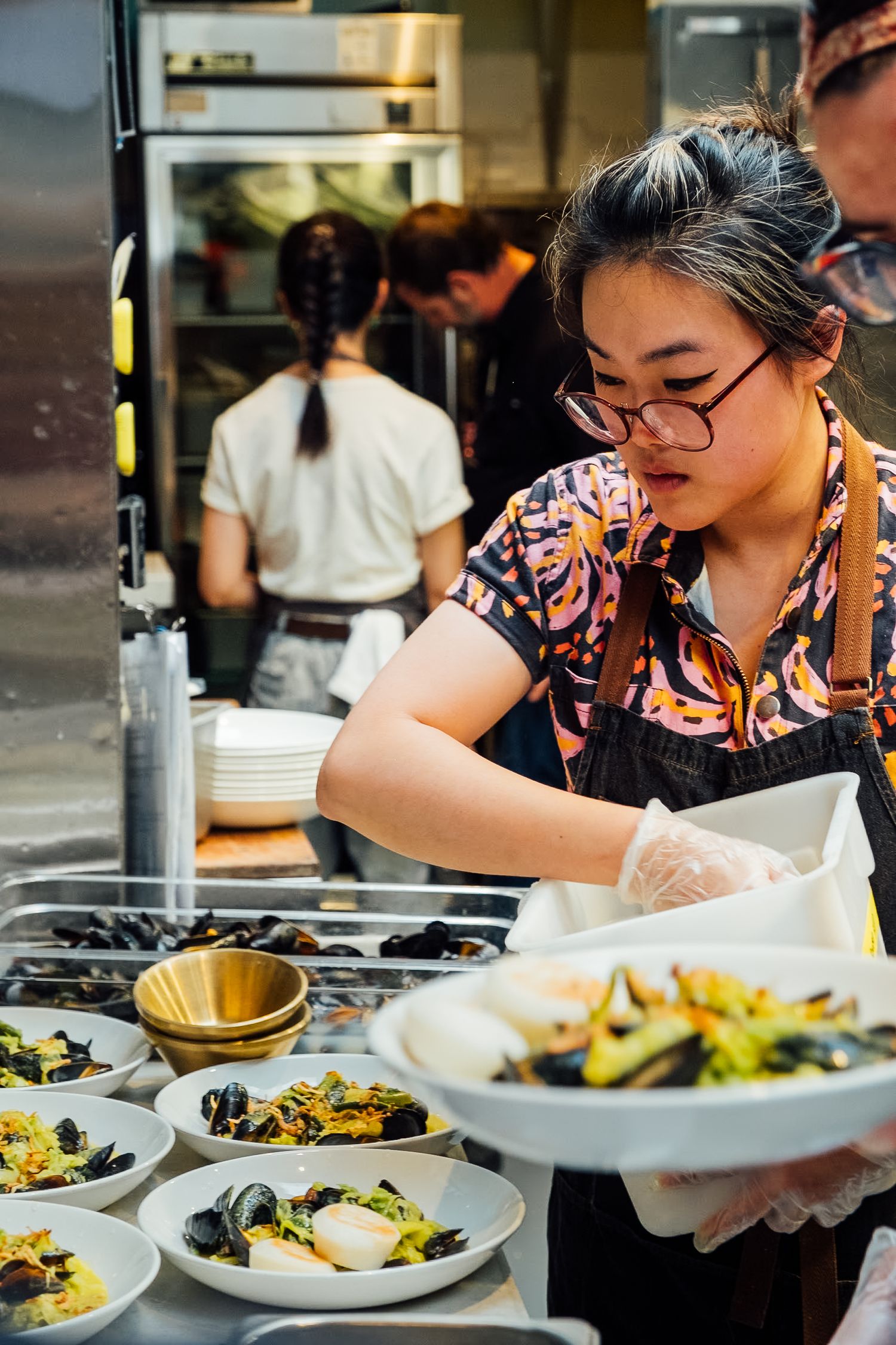 Food service worker preparing fresh dishes at restaurant serving station.
