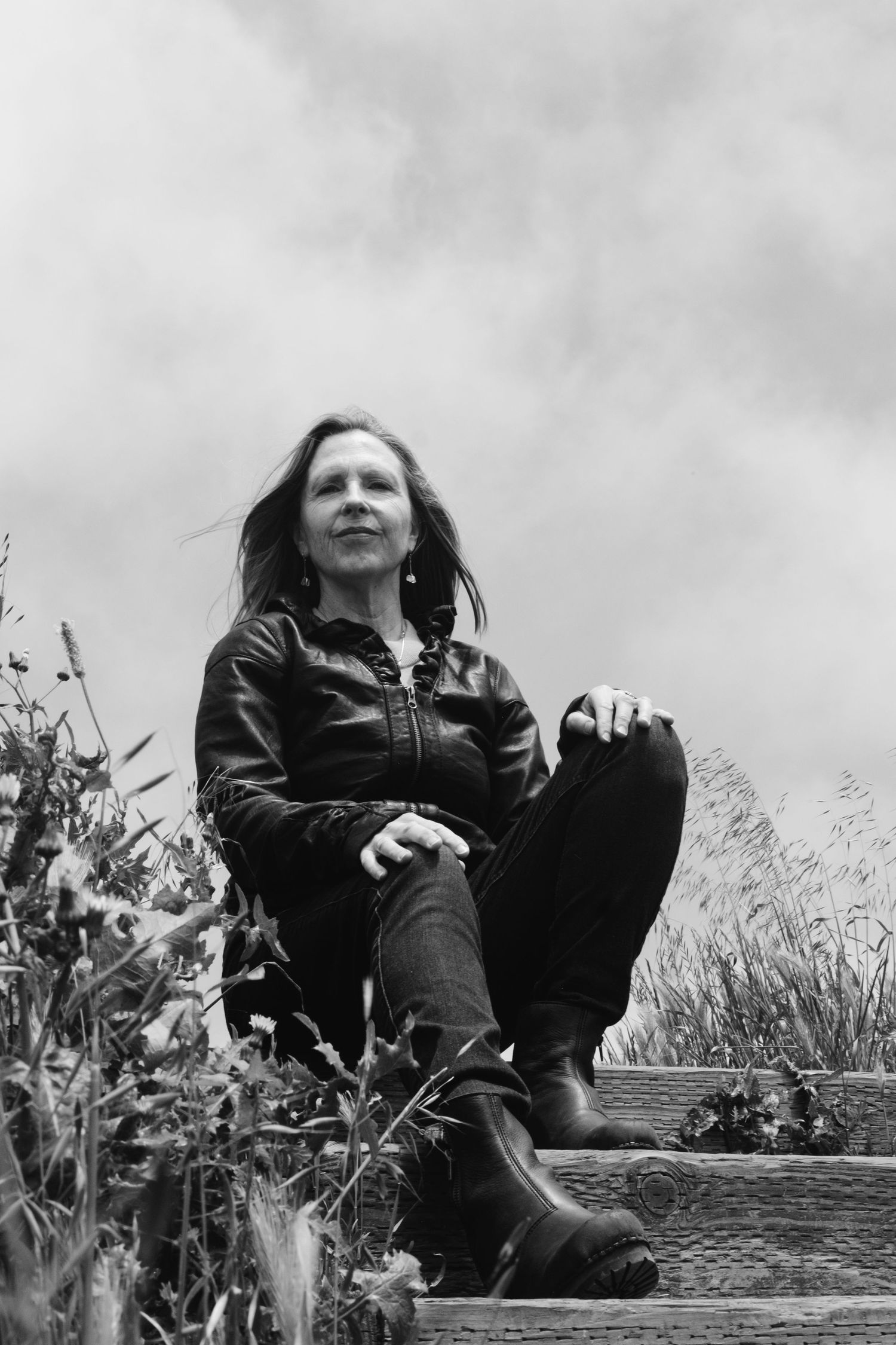 Black and white portrait series showing someone seated outdoors among tall grass and plants.