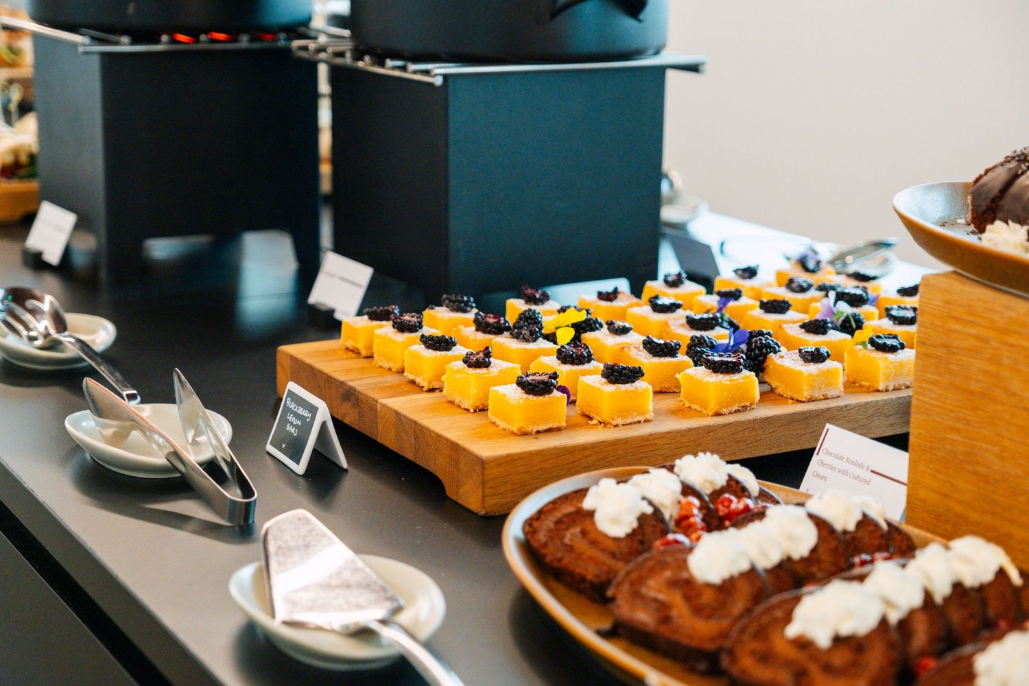 Elegant dessert display featuring chocolate mousse, fresh fruit tarts, and pastries arranged on wooden serving boards.