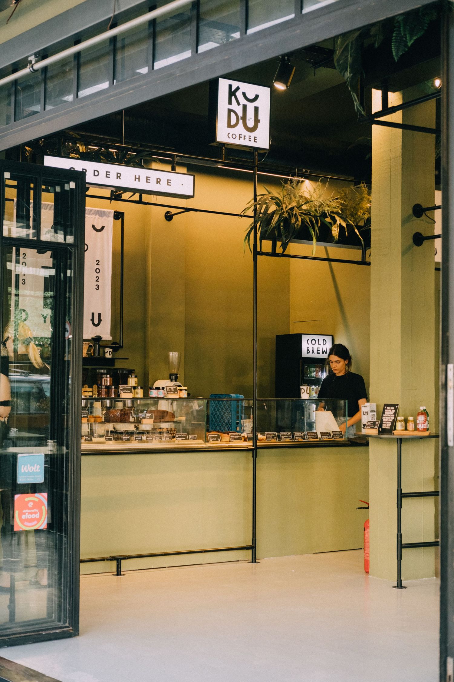 Modern minimalist cafe interior with KYUI branding and counter service design.