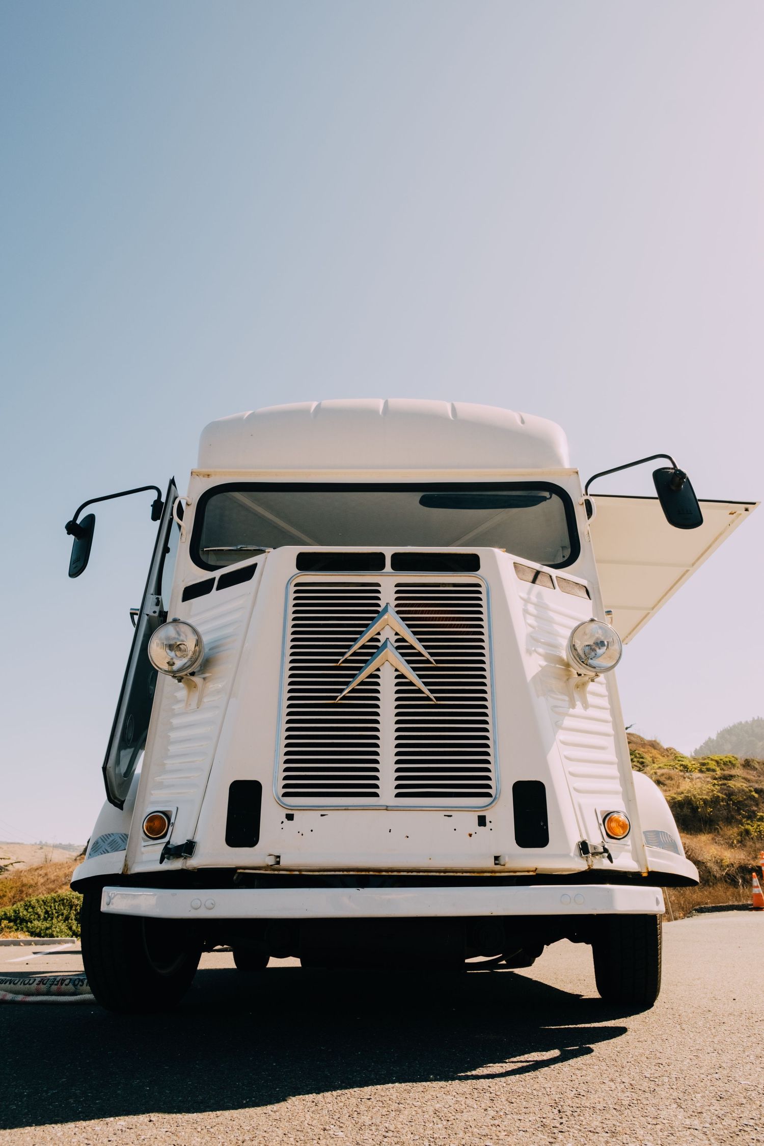 Front view of a classic white Citroen food truck against a bright blue sky.