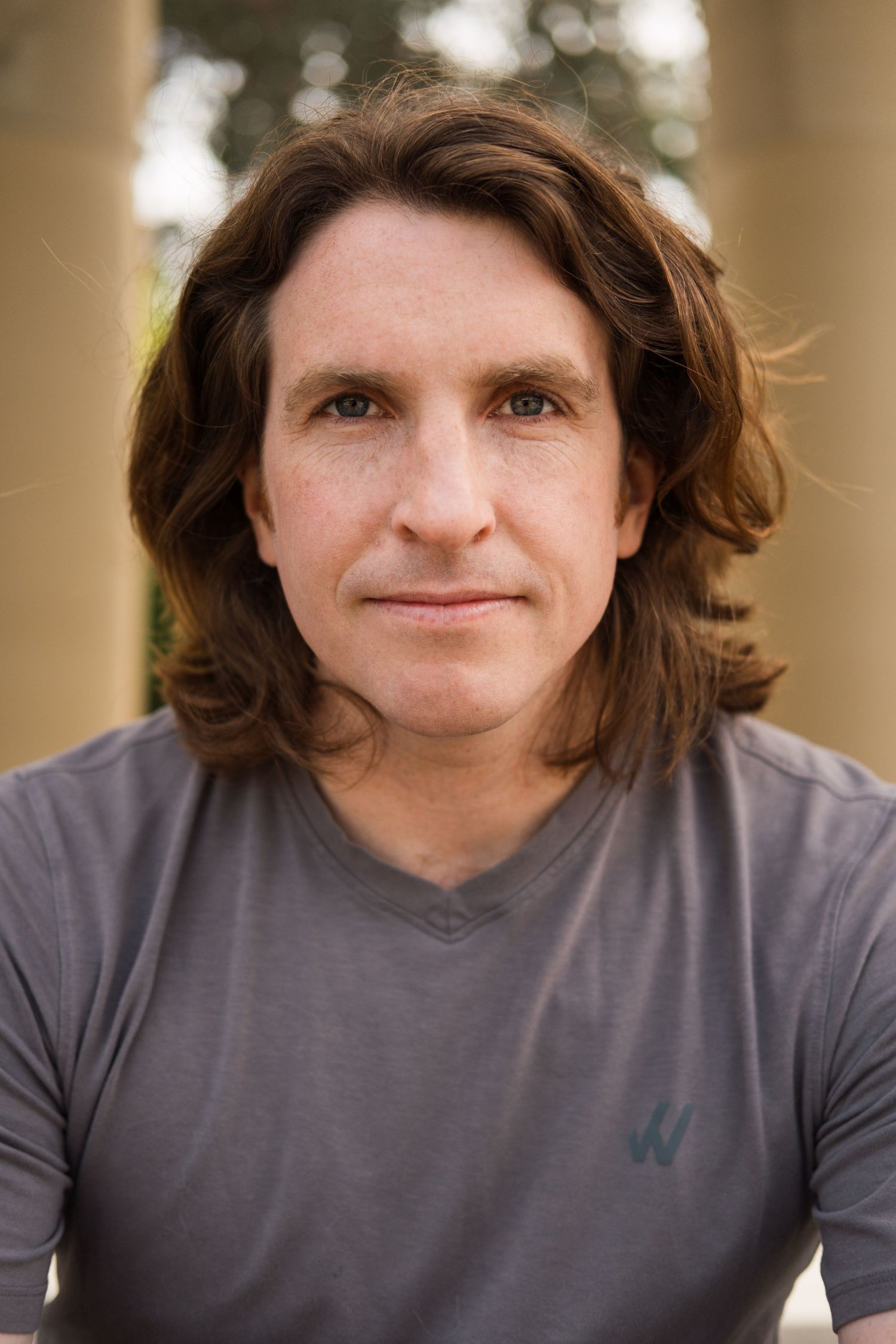 Serious actor headshot, man with shoulder-length hair looking straight into camera. SF Bay Area outdoor lifestyle headshot.