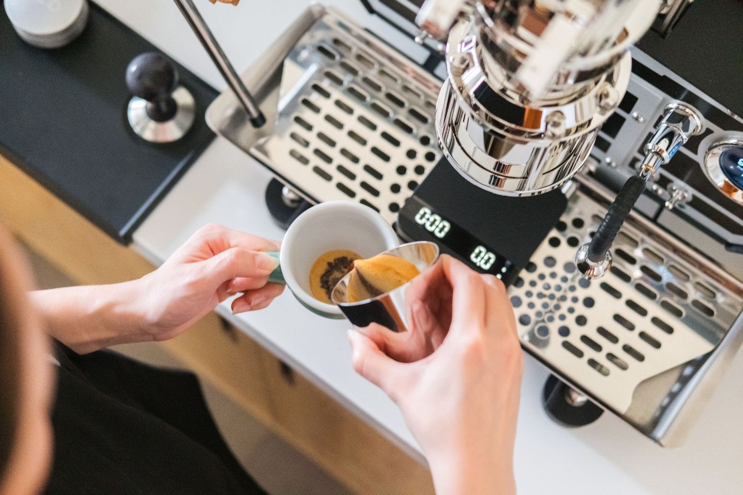 Close-up shots of hands operating an espresso machine and preparing coffee drinks.