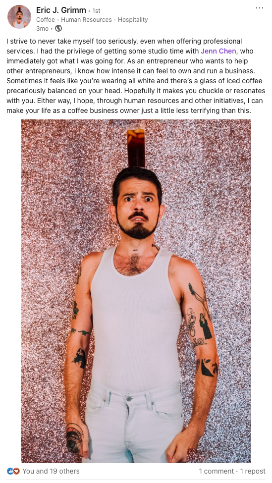 Person wearing white tank top with tattoos poses against sparkly silver backdrop in business-related social media post.