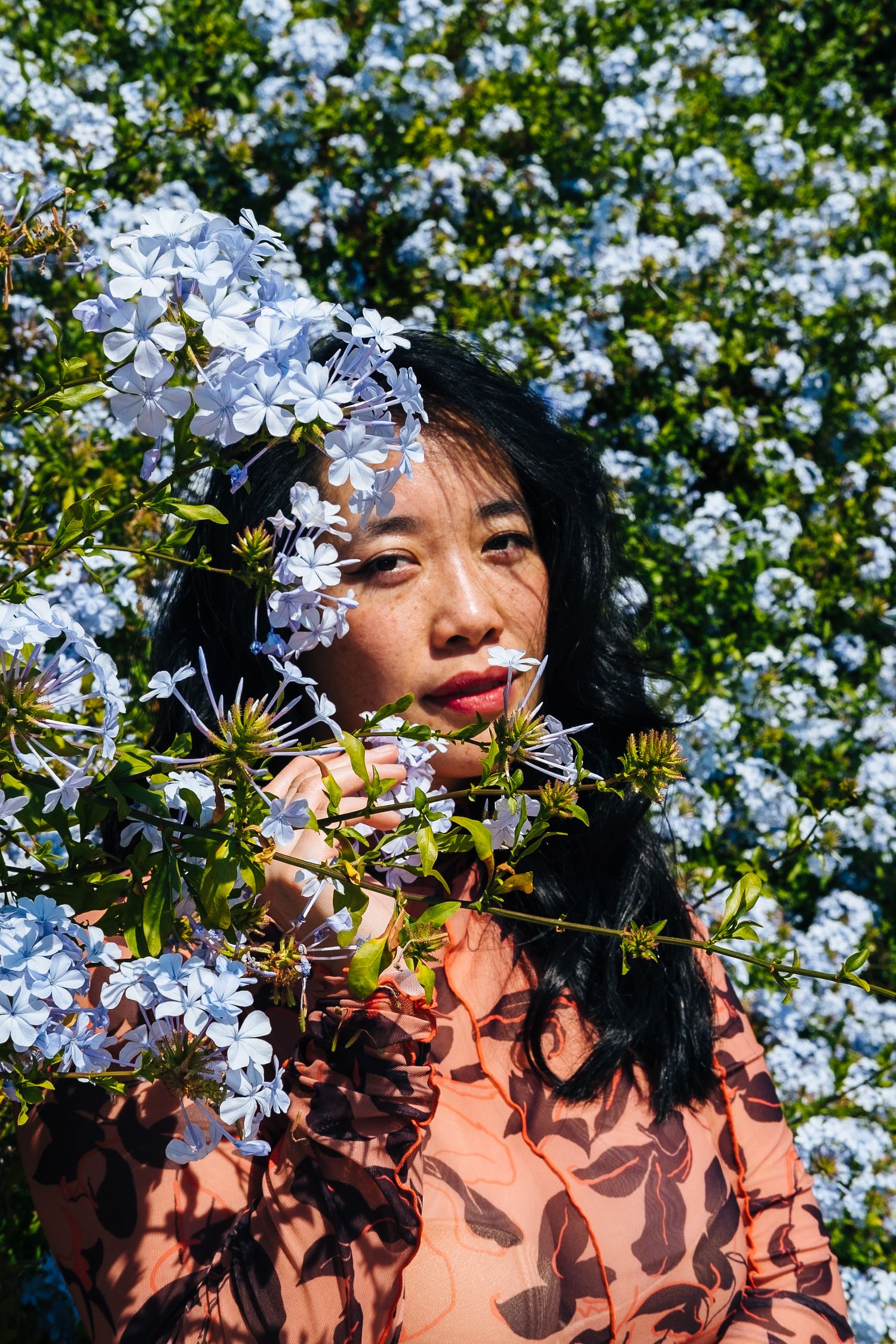 Colorful, outdoor, creative portrait of an Asian-American woman, among flowers,taken by professional photographer Jenn Chen in San Francisco
