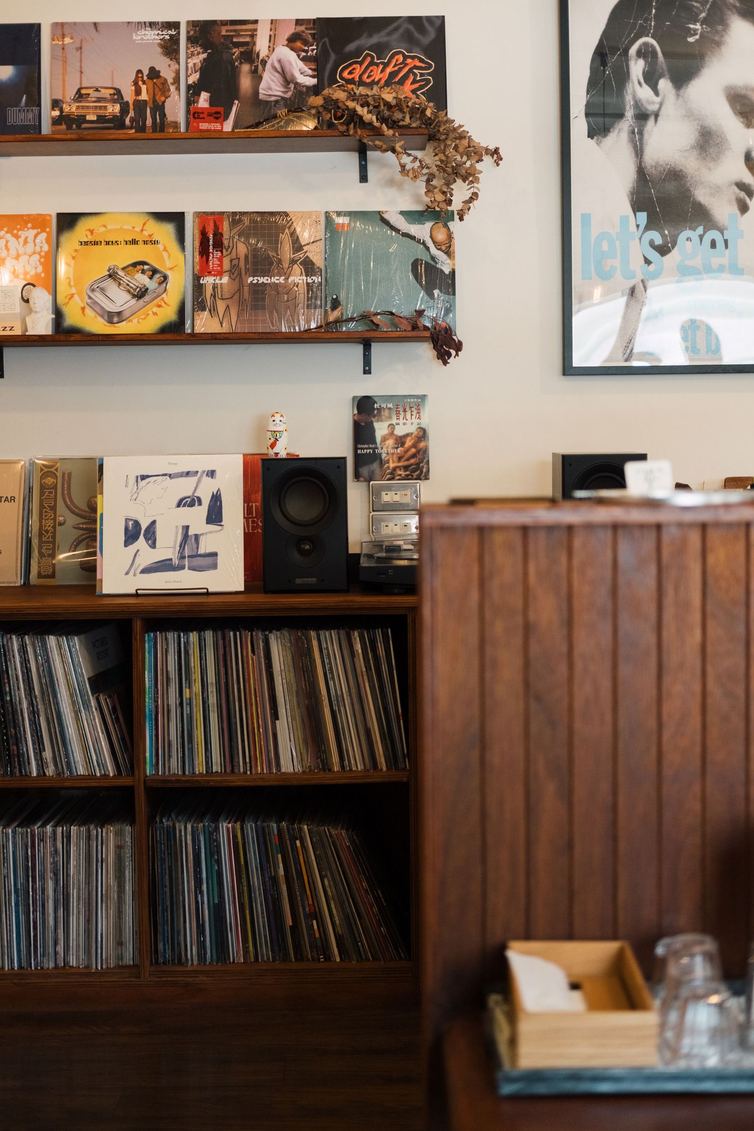 Vintage record collection displayed on wooden shelves with posters and artwork on the wall above.