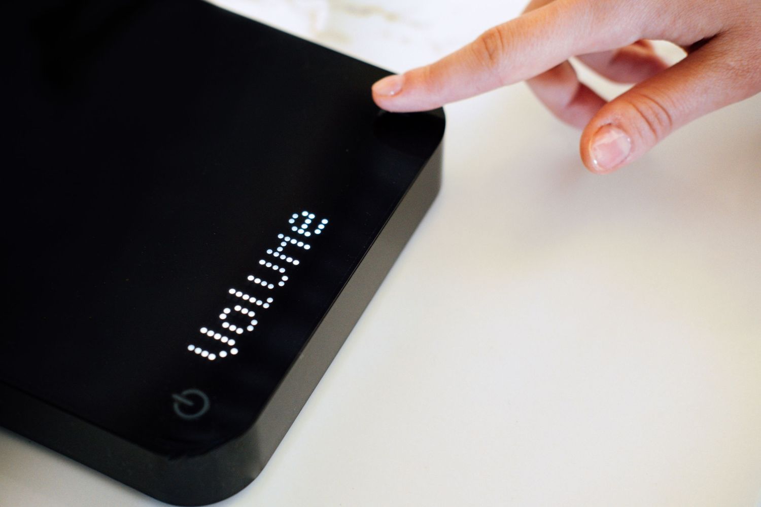 Close up of a finger touching a black electronic scale display.